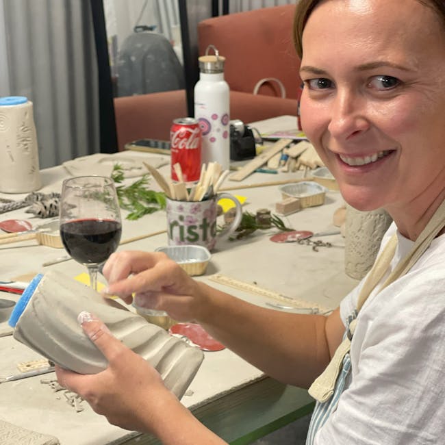 Nic enjoying a glass of wine while creating a masterpiece in clay