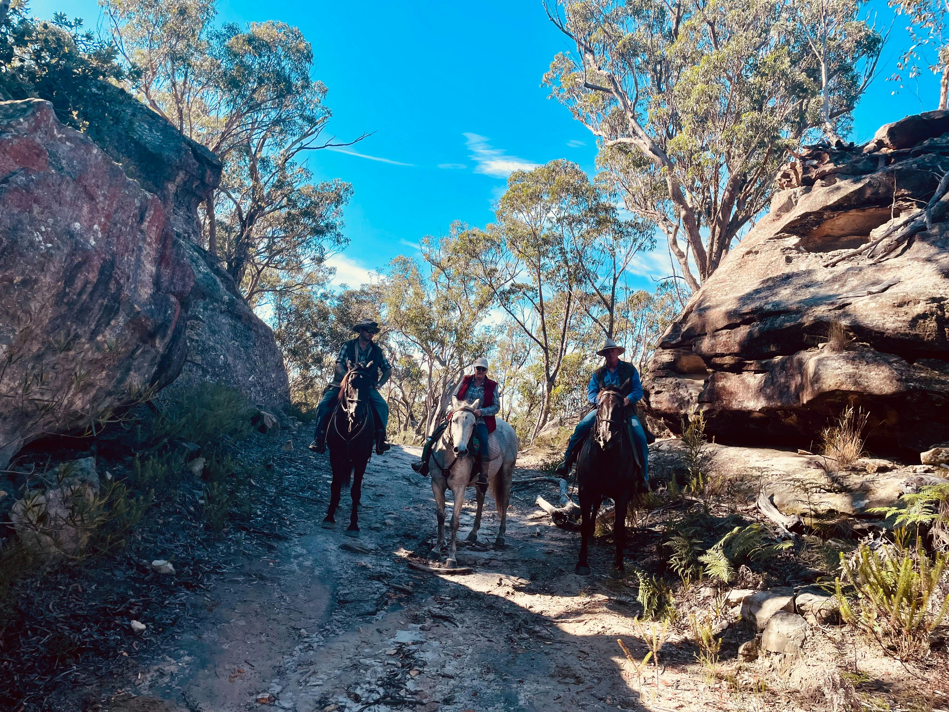 horse riders near rocky caves