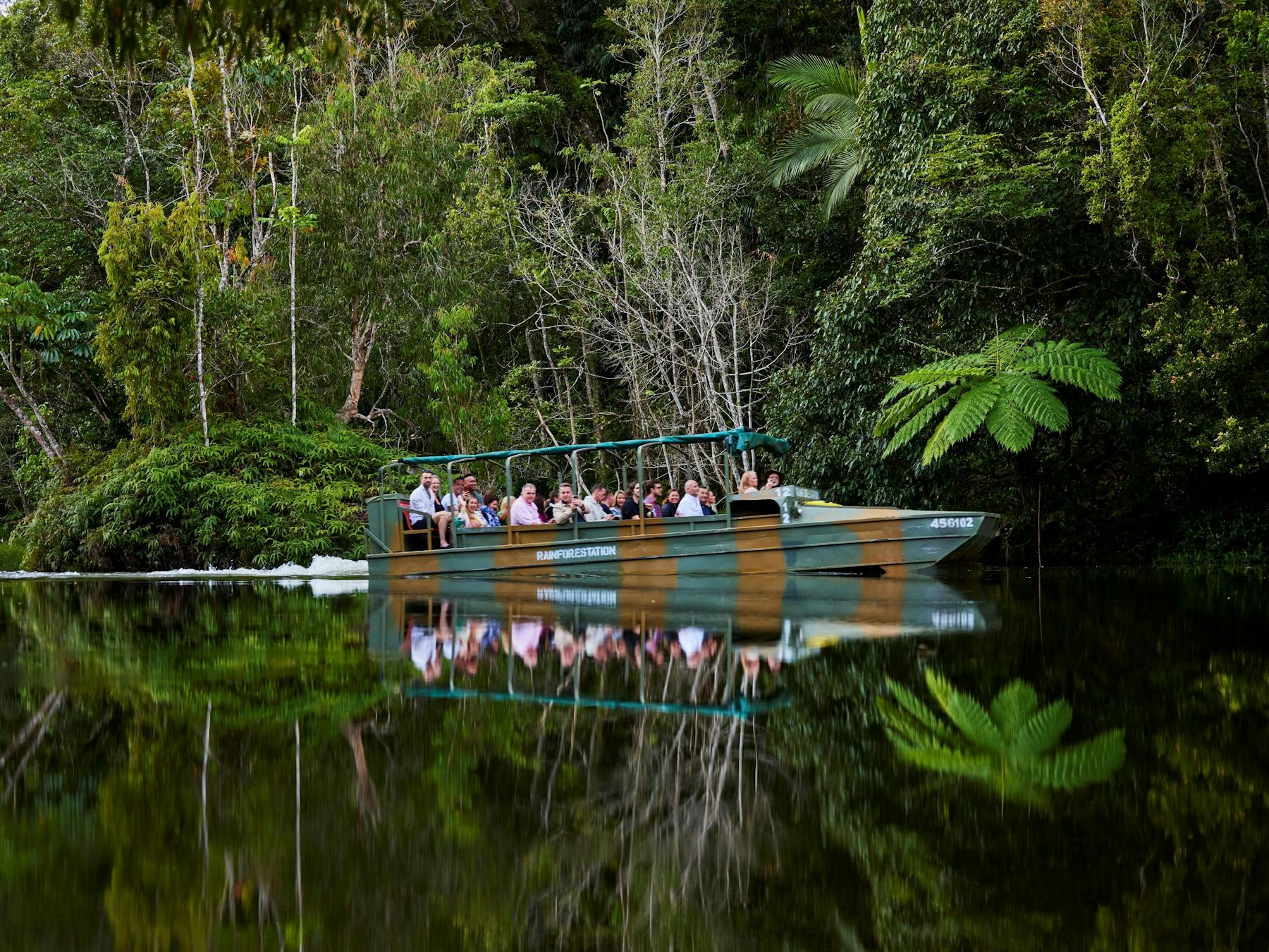 An amphibious Army Duck cruising on a lake amongst the rainforest, passengers enjoying the serenity