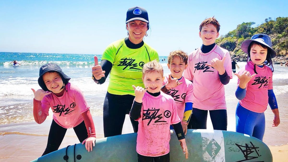 Coach and 5 kids pose after surf lesson
