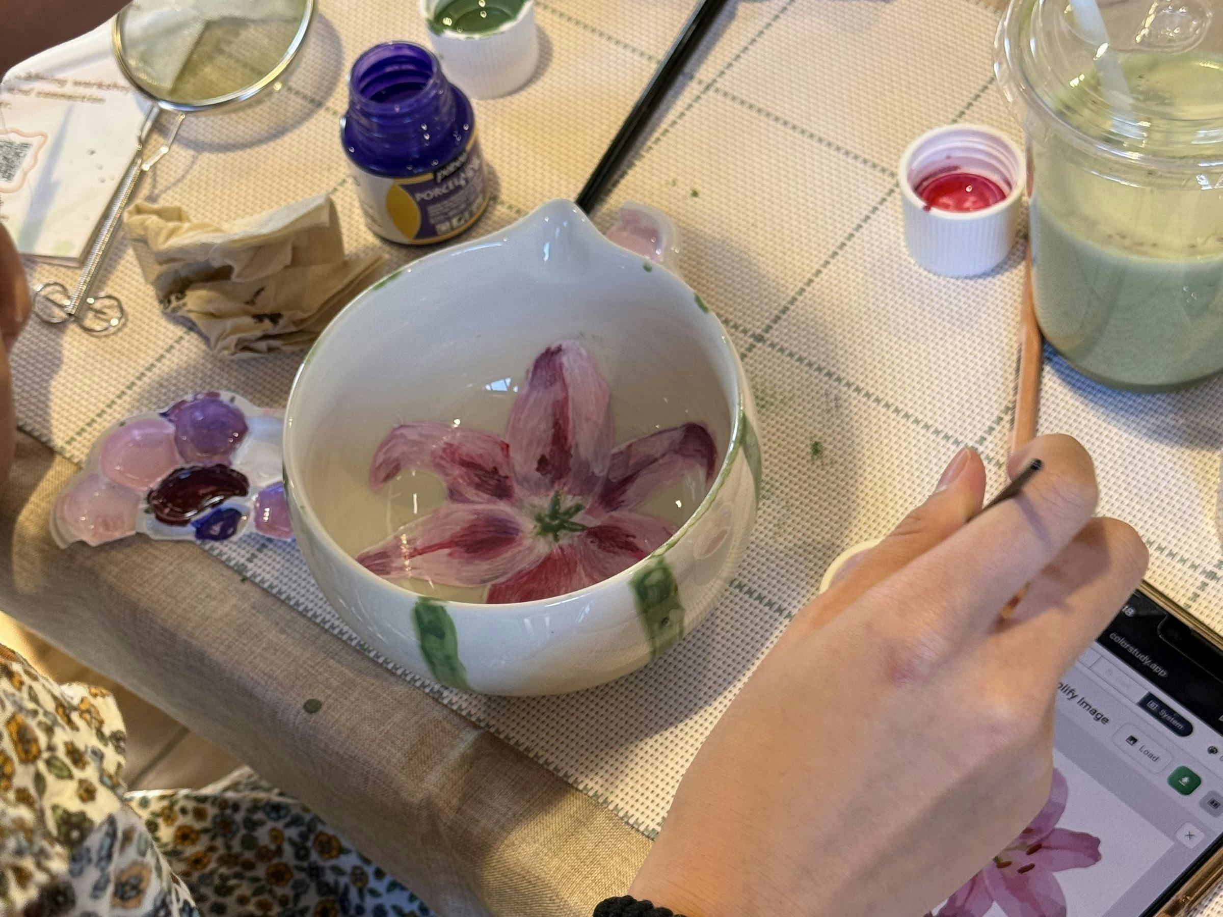 Guest hand-painting a ceramic cup at a NOA Matcha workshop