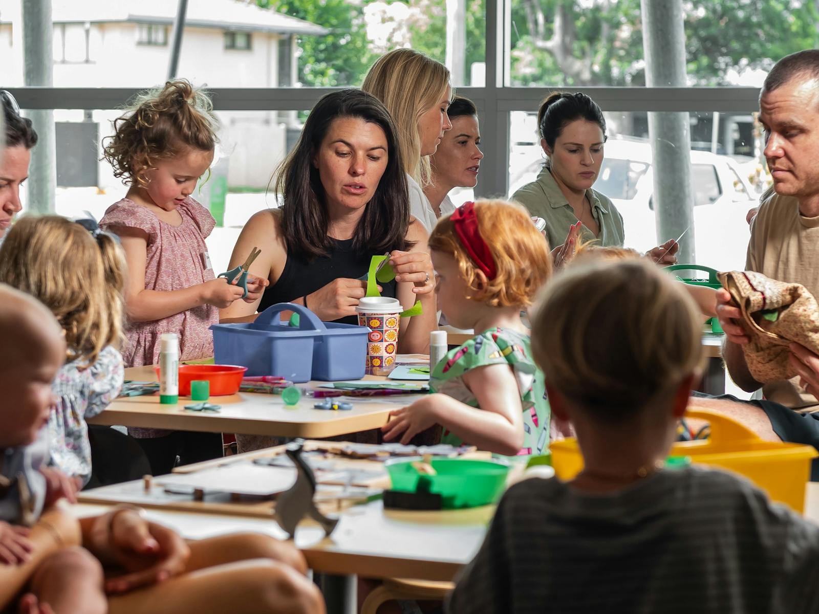 Parents and children sit at tables together and use crafts. Parents and children sit at tables together and use crafts.