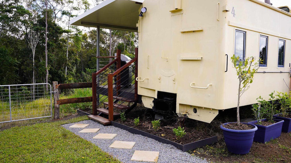 The Ghan train carriage, transformed into a luxury stay with a private deck and scenic countryside.