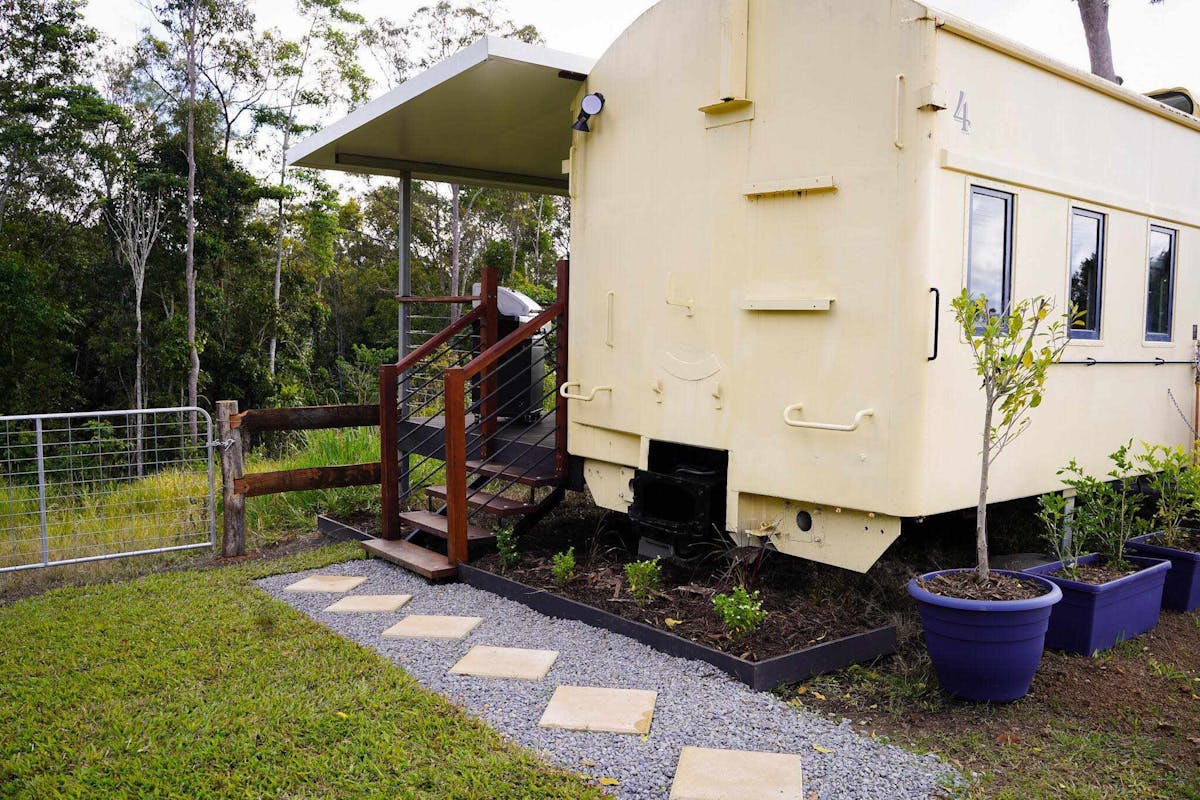 The Ghan train carriage, transformed into a luxury stay with a private deck and scenic countryside.