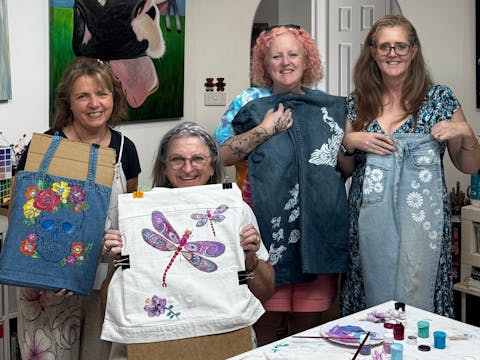 group holding up their denim paintings