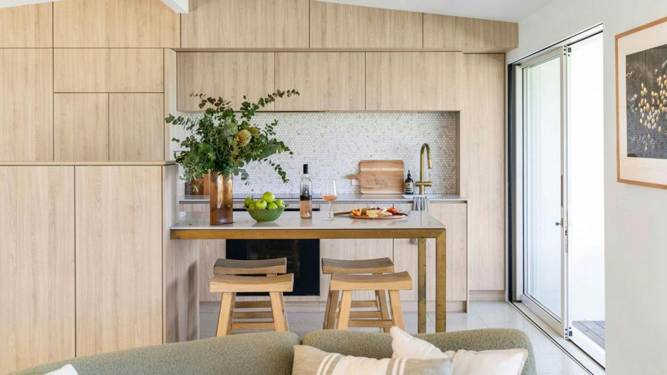 View of kitchen with modern finishes and a bottle of rose and a cheese platter sit on the bench