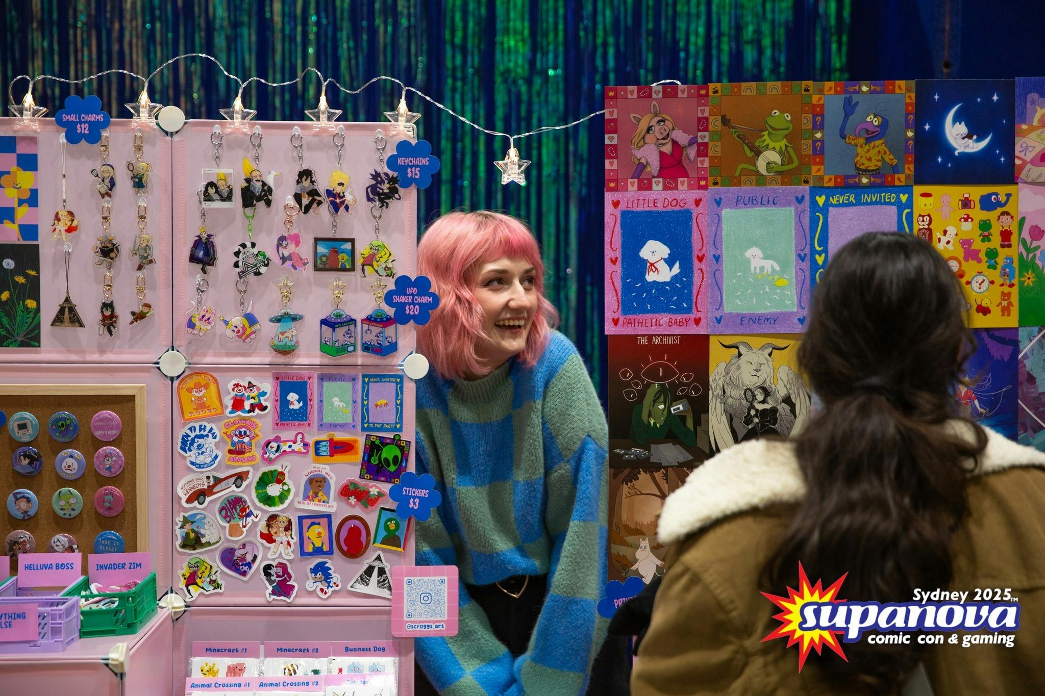 Artist speaking with an attendee at a colourful market stall.