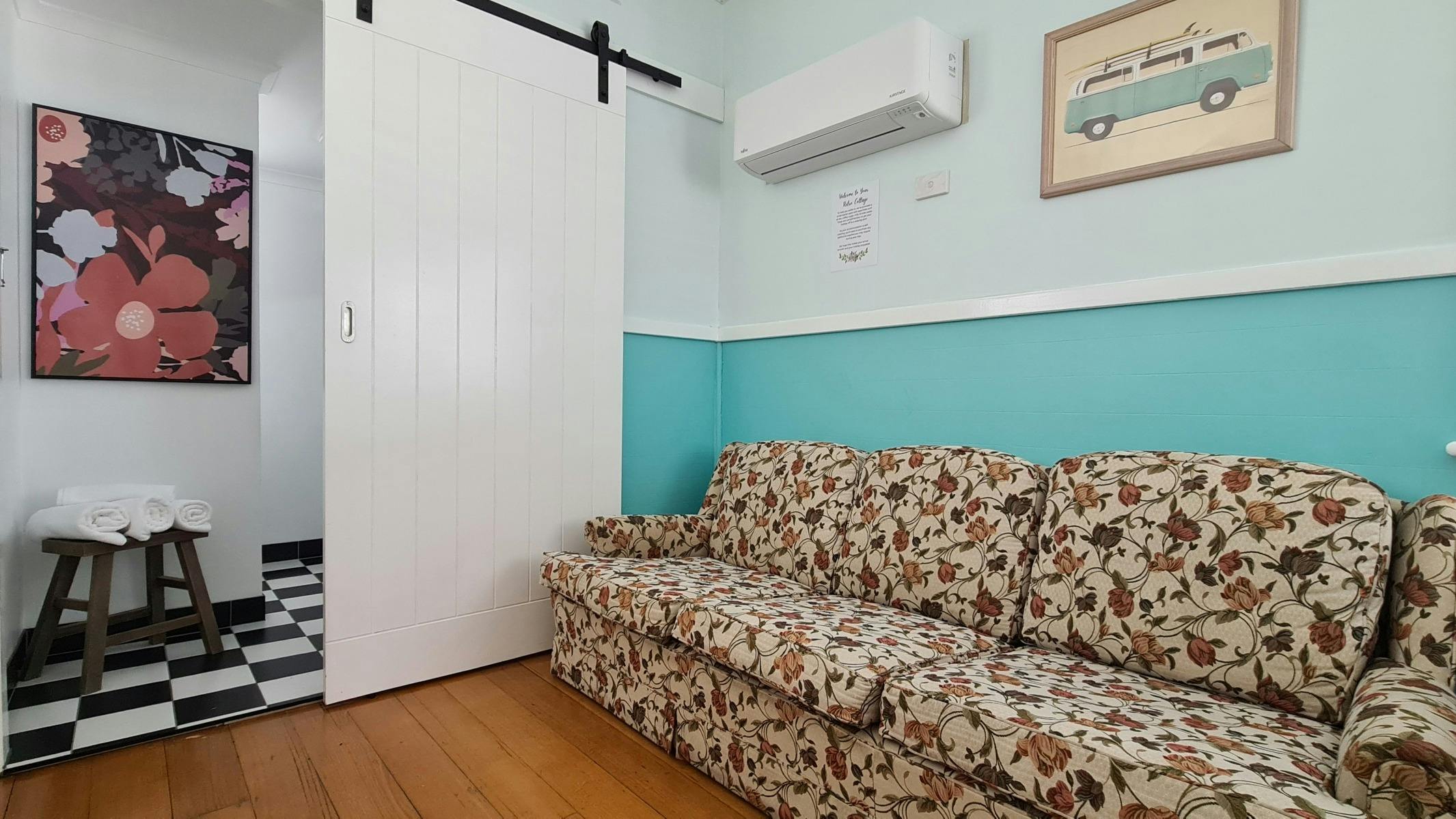 Image of couch under an air conditioner & barn door peeking through to a modern bathroom