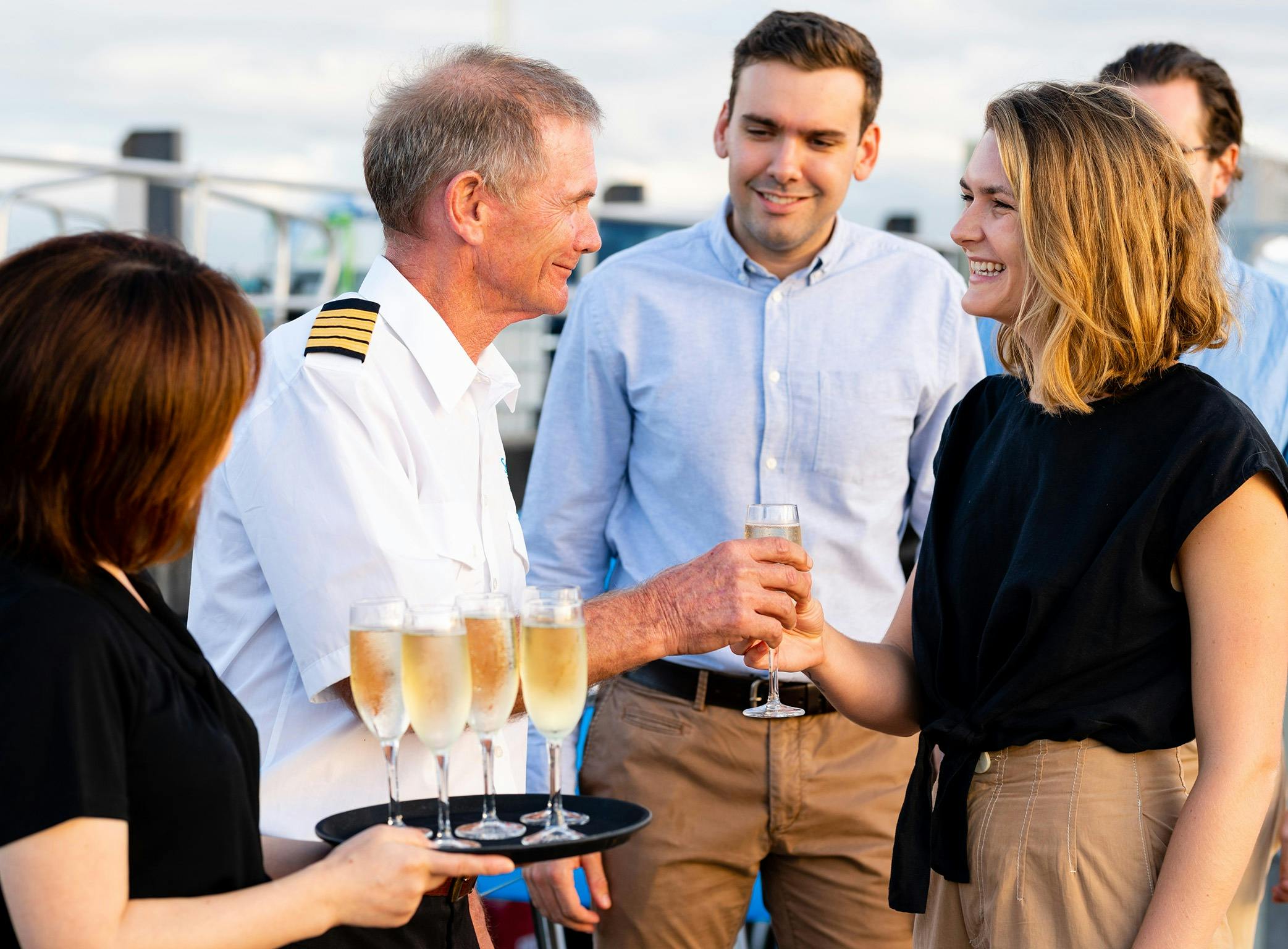 Captain greeting guests upon arrival onboard offering a glass of bubbles