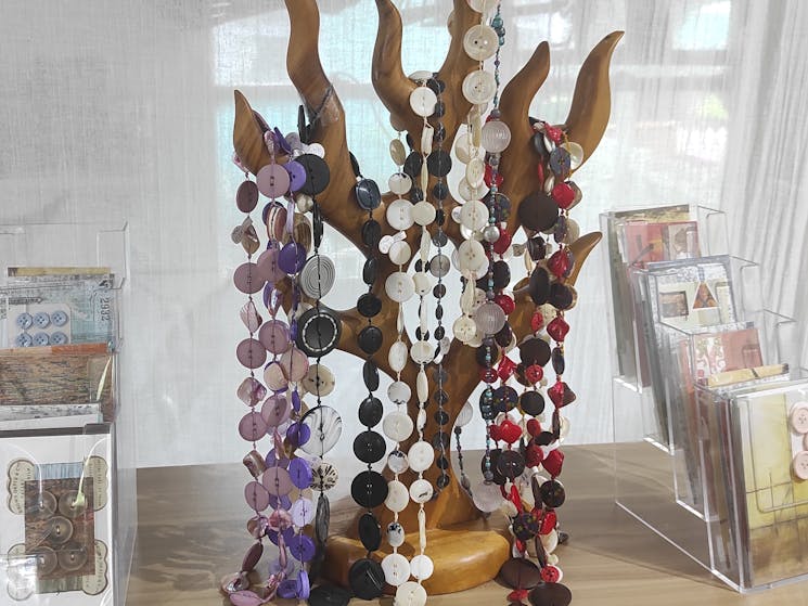 Display of Button necklaces hanging on wooden stand,  and cards by Mary Gilmour