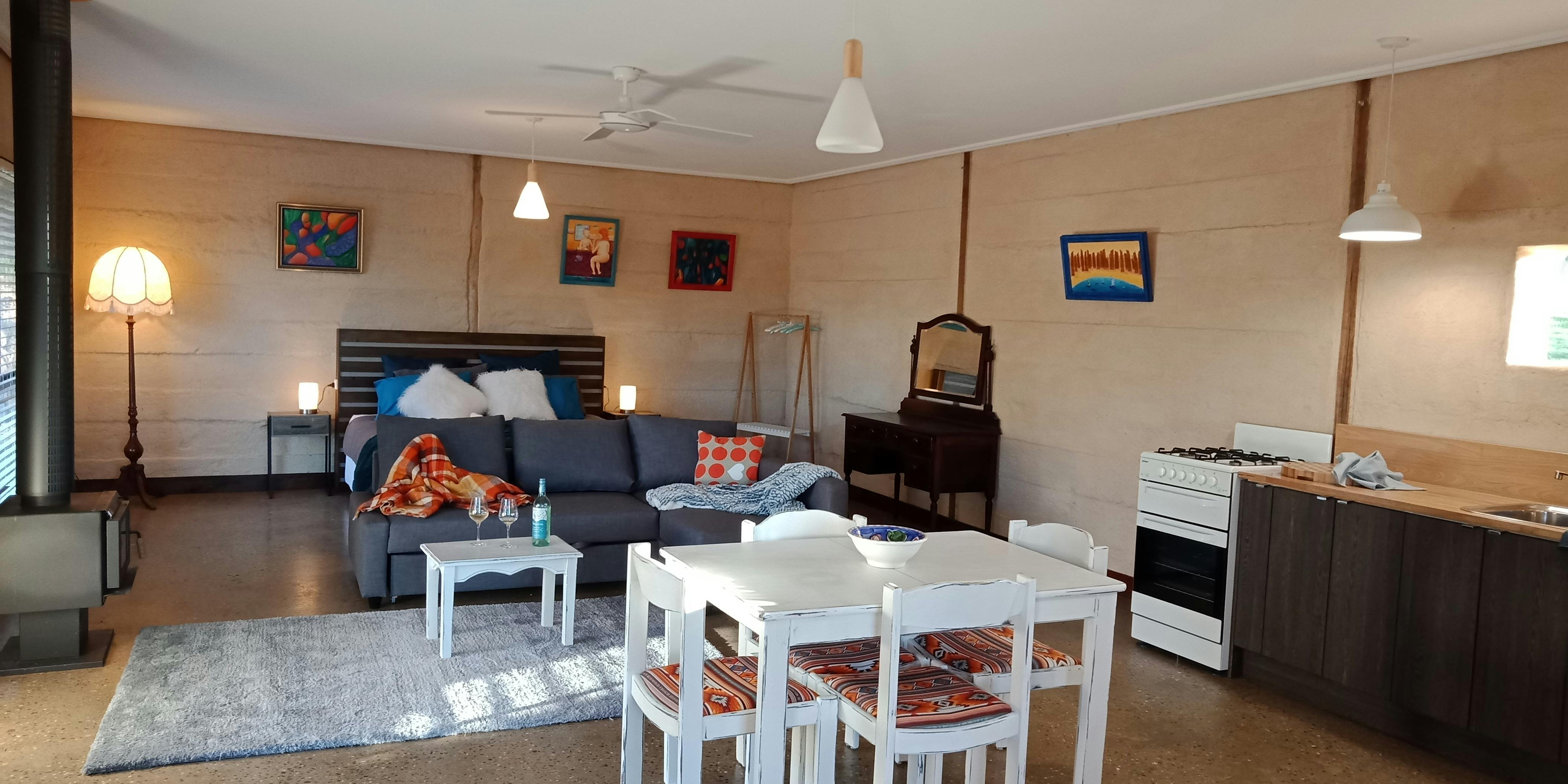 Large open plan cottage with table and chairs, couch, and king bed .