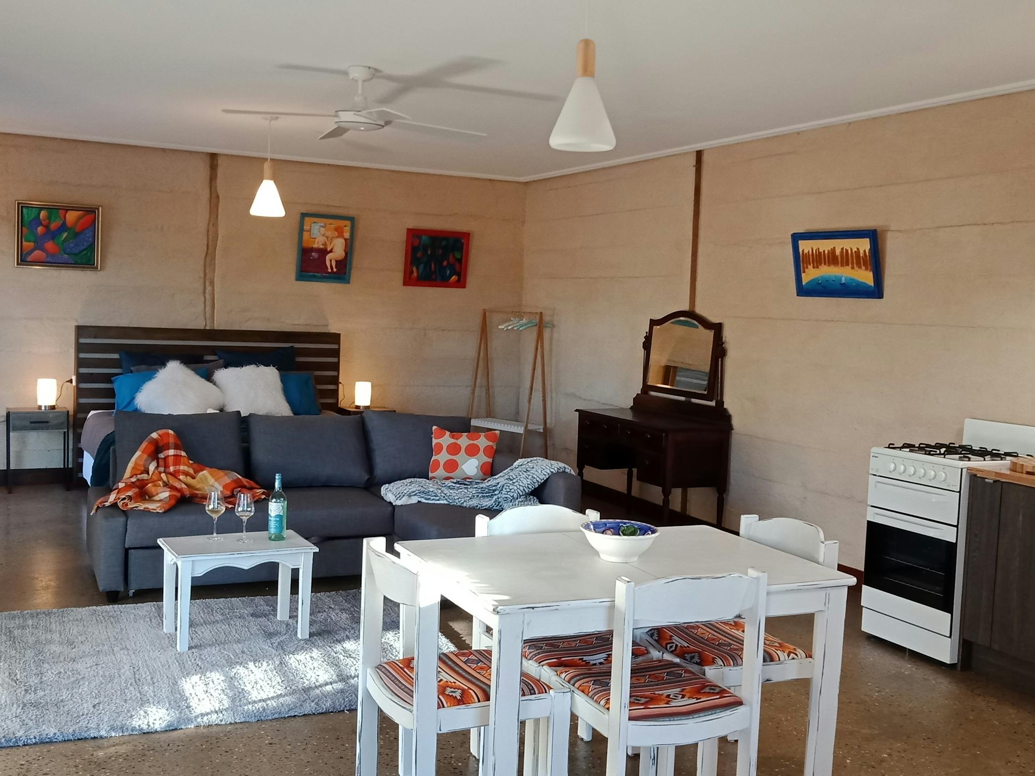 Large open plan cottage with table and chairs, couch, and king bed .