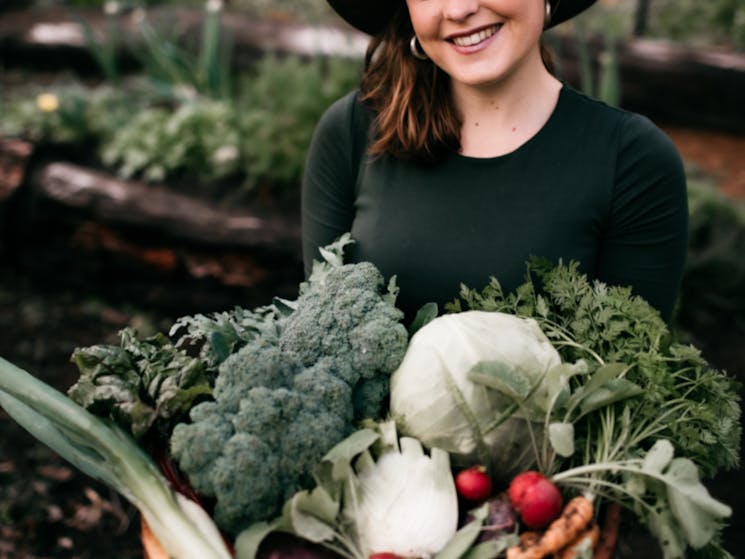 Katie holding an armful of fresh vegetables