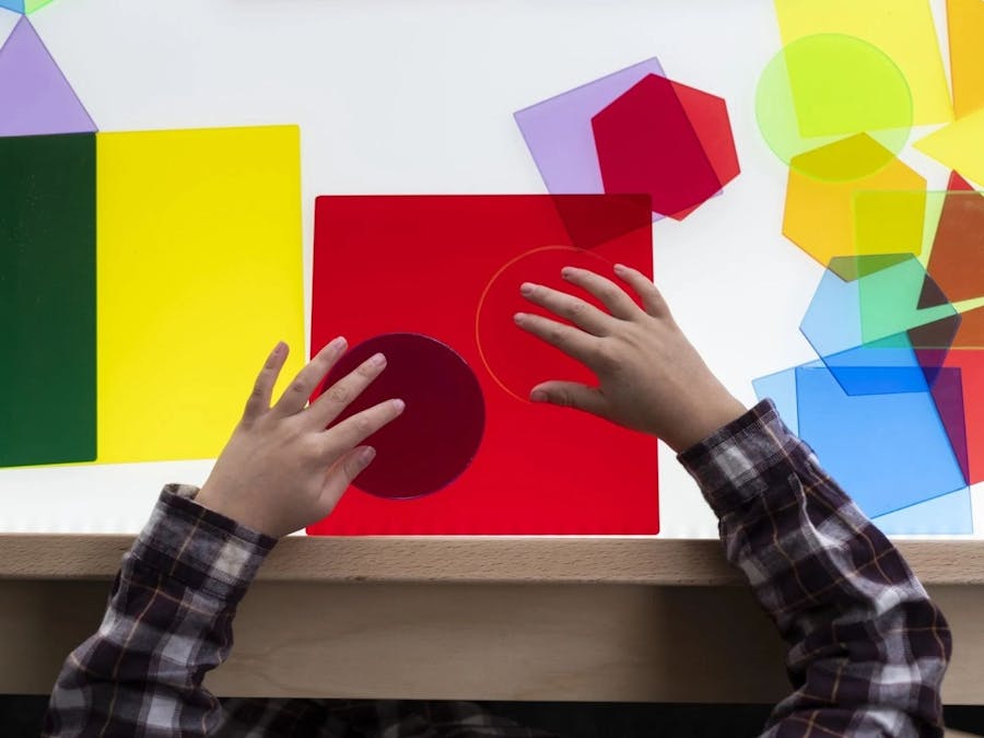 Aerial view of a child playing with multi colour shape cut outs as part of Creative Play