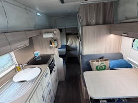 Interior view of Jayco Expanda. Shows sink, cooktop, seating and bunk with additional seeing below