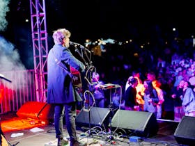 single performer, Josh Pyke plays guitar on a stage in front of a crowd