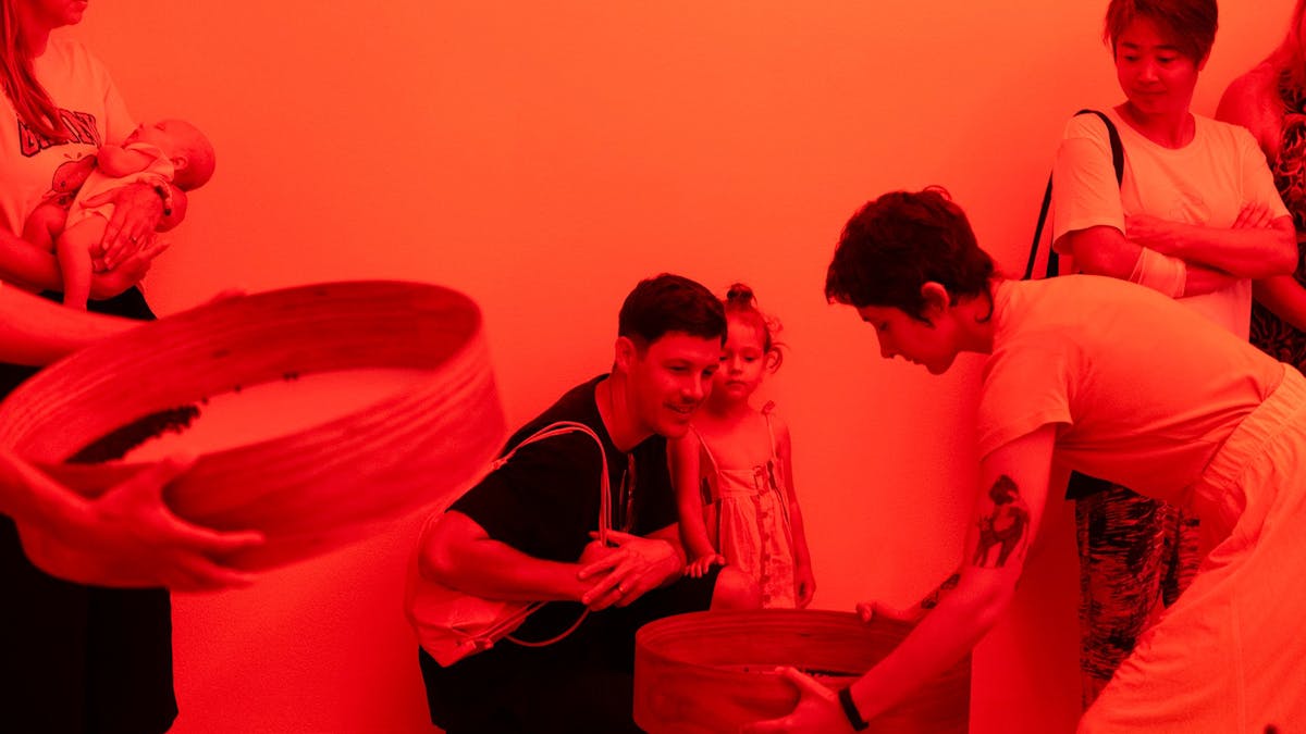 Woman with a wooden tray bends down to show man and small child