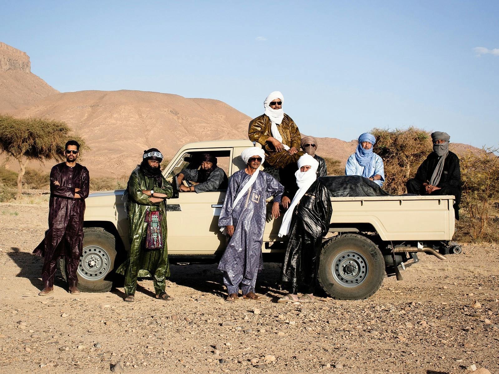 A group of people standing next to a ute in the desert