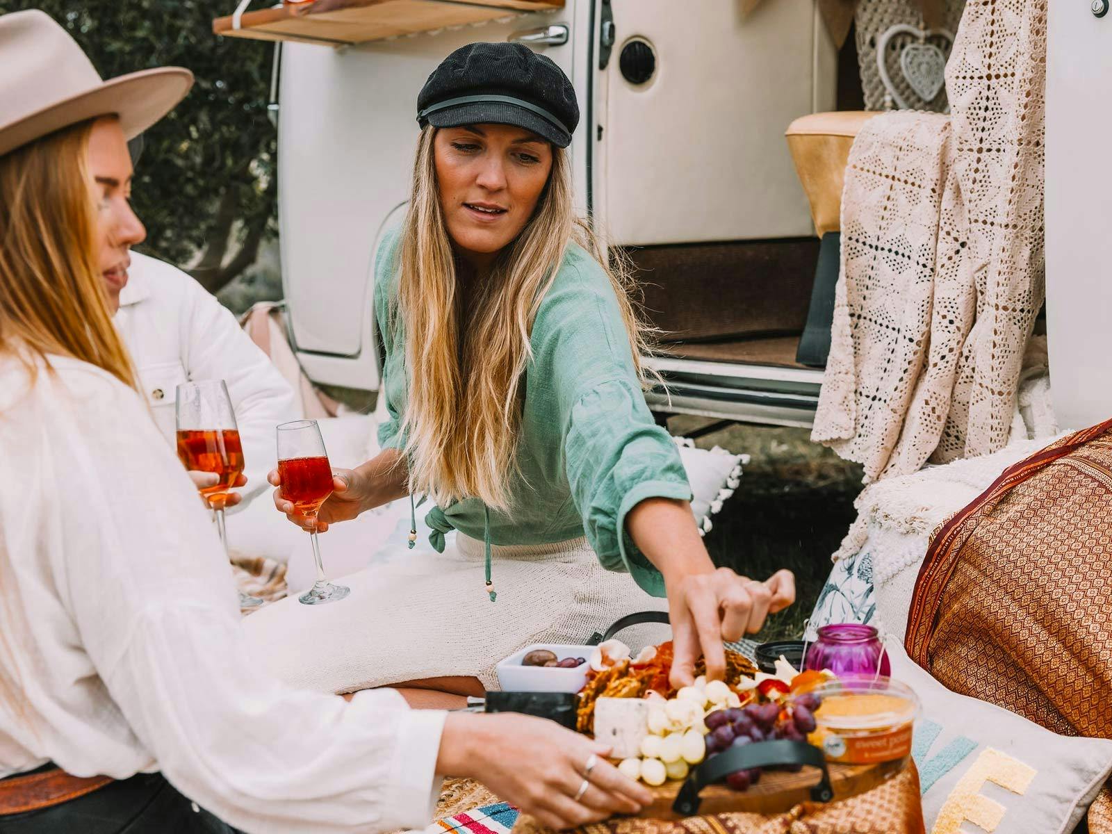 Tewo young ladies drinking a glass of wine whilst nibbling on a grazing platter
