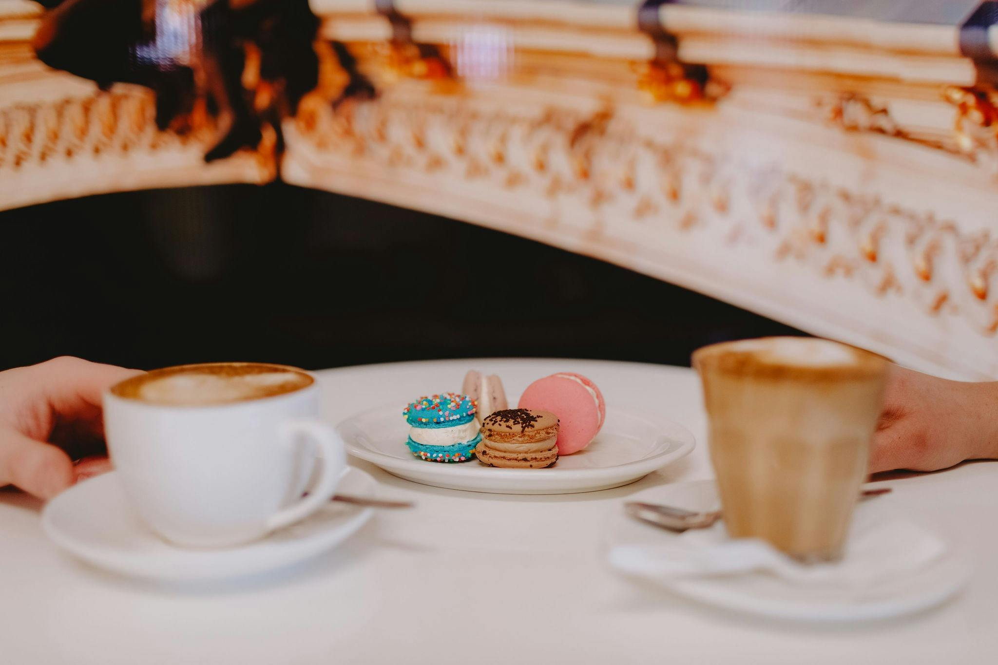 A tablescape with pink, blue and chocolate macaroons and two coffees either side