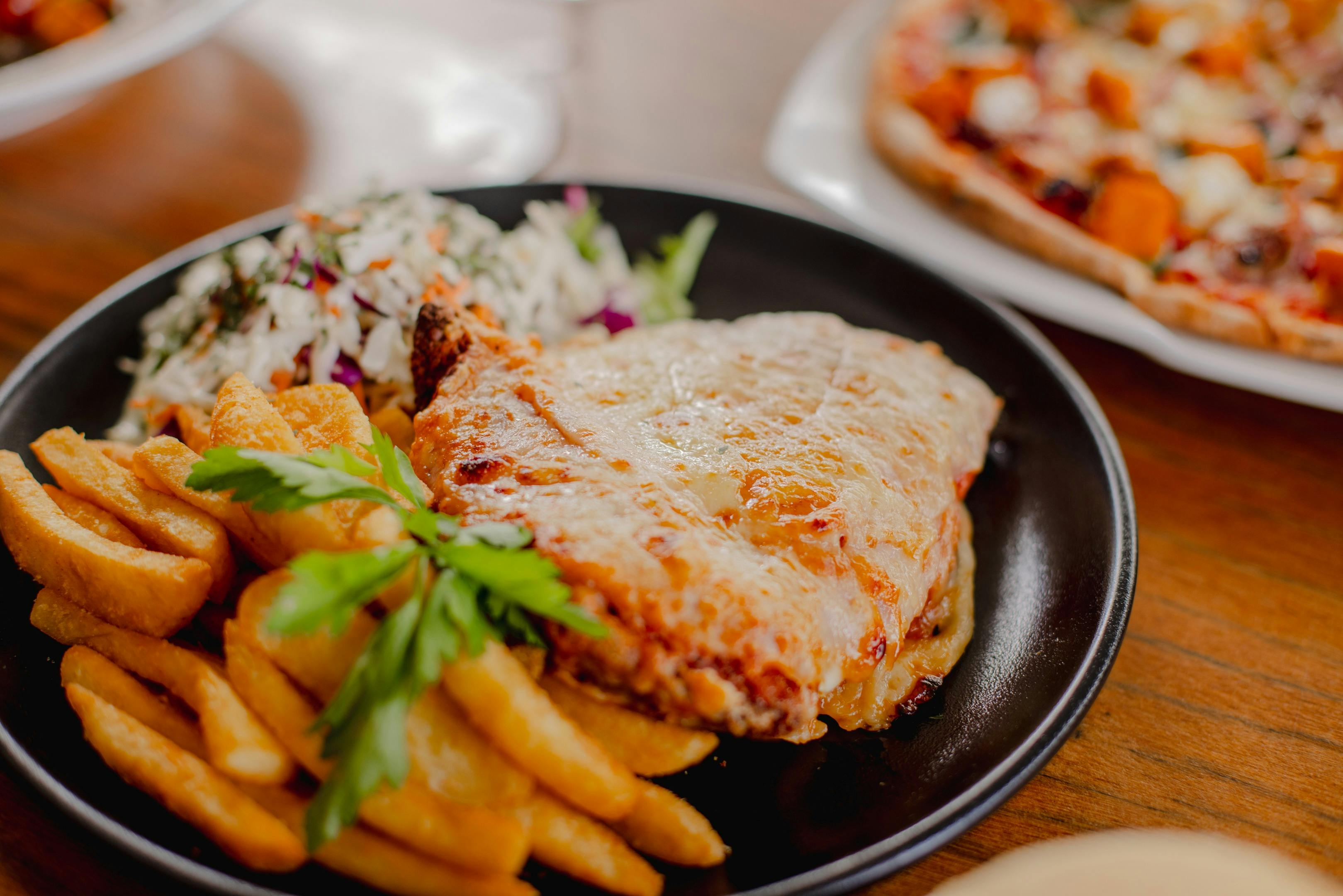 Plate of chicken parmigiana, chips and salad on a table at Orion Hotel Springfield