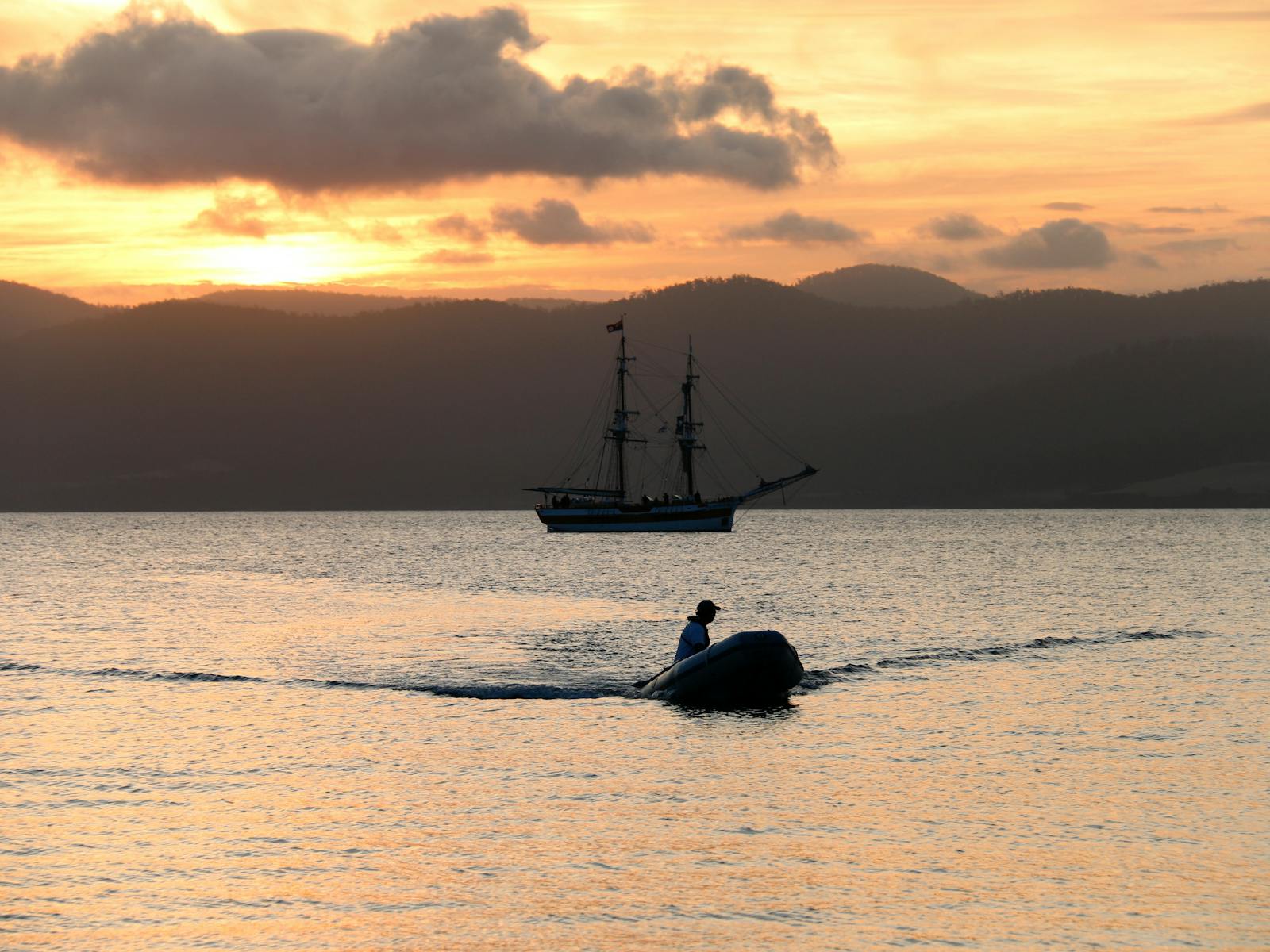 sunset over the Lady Nelson with the rib heading towards the beach at sunset