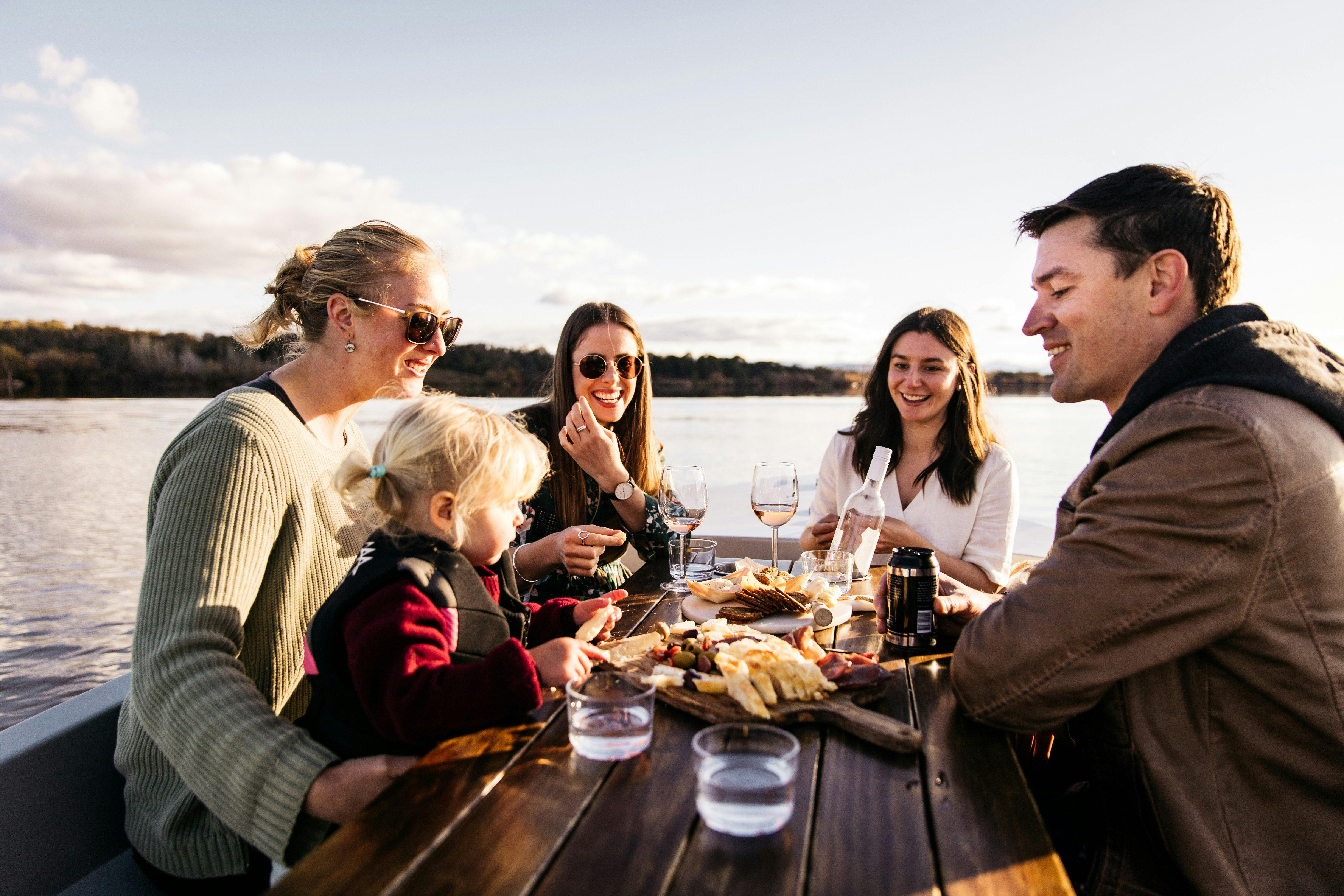 Four adults and a female child having a picnic on a boat