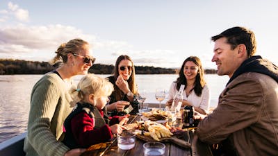 Four adults and a female child having a picnic on a boat