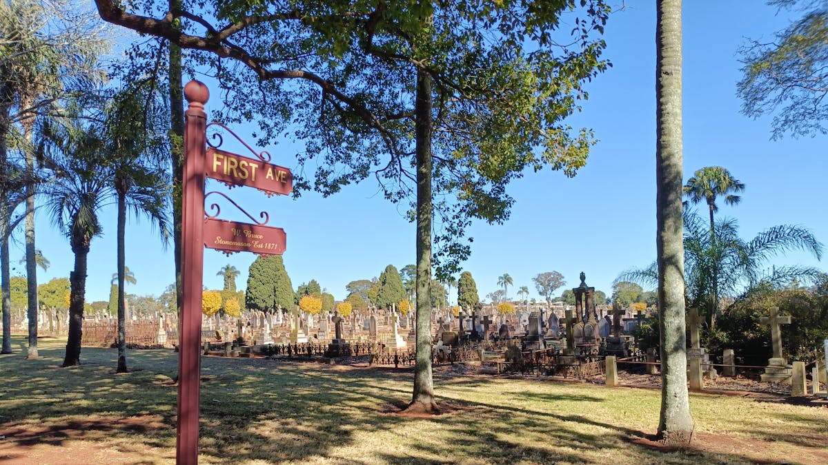A sign that reads 'First Avenue' with historic graves in the background