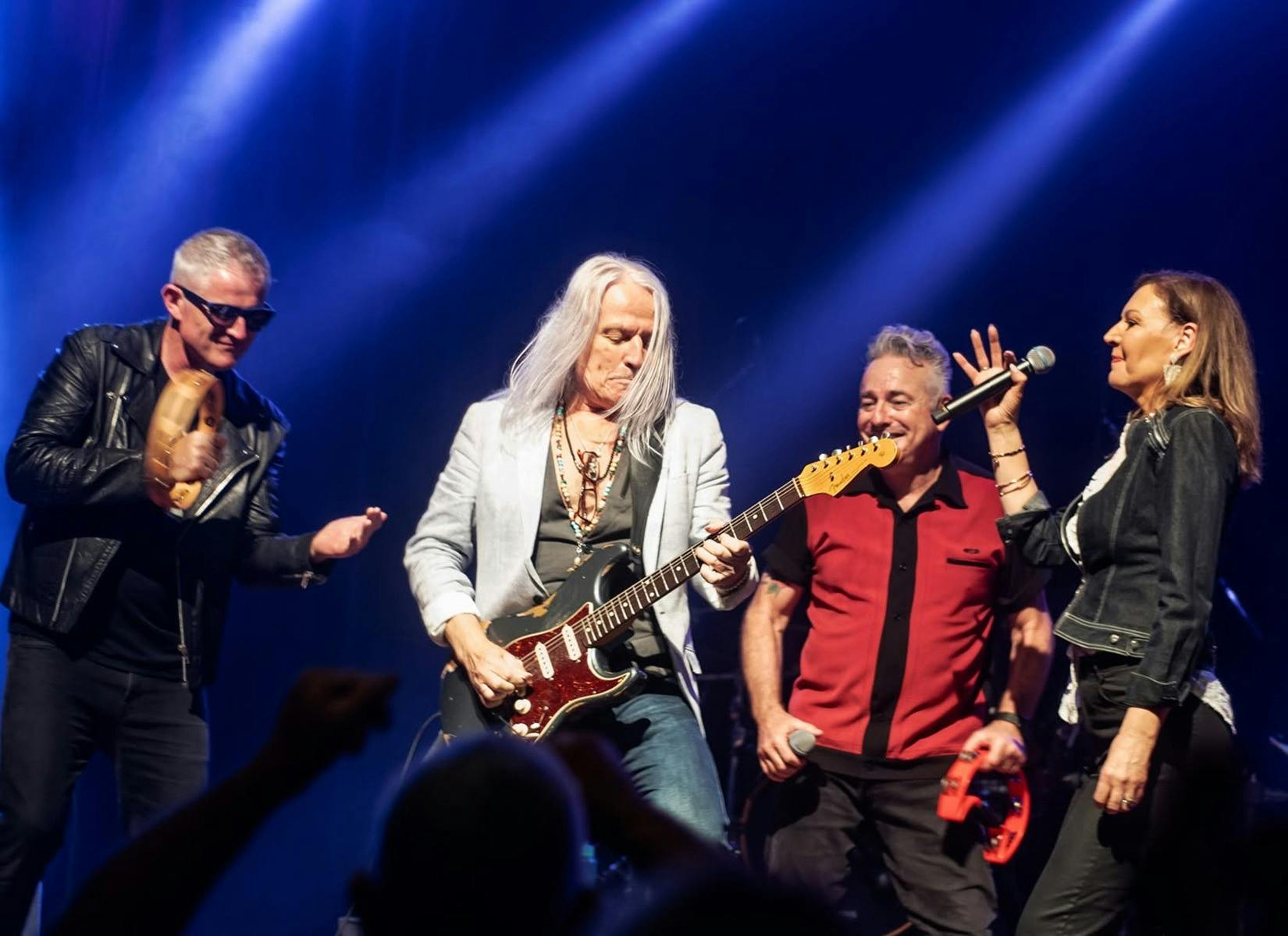 Four grey hair rockers and one women on stage performing