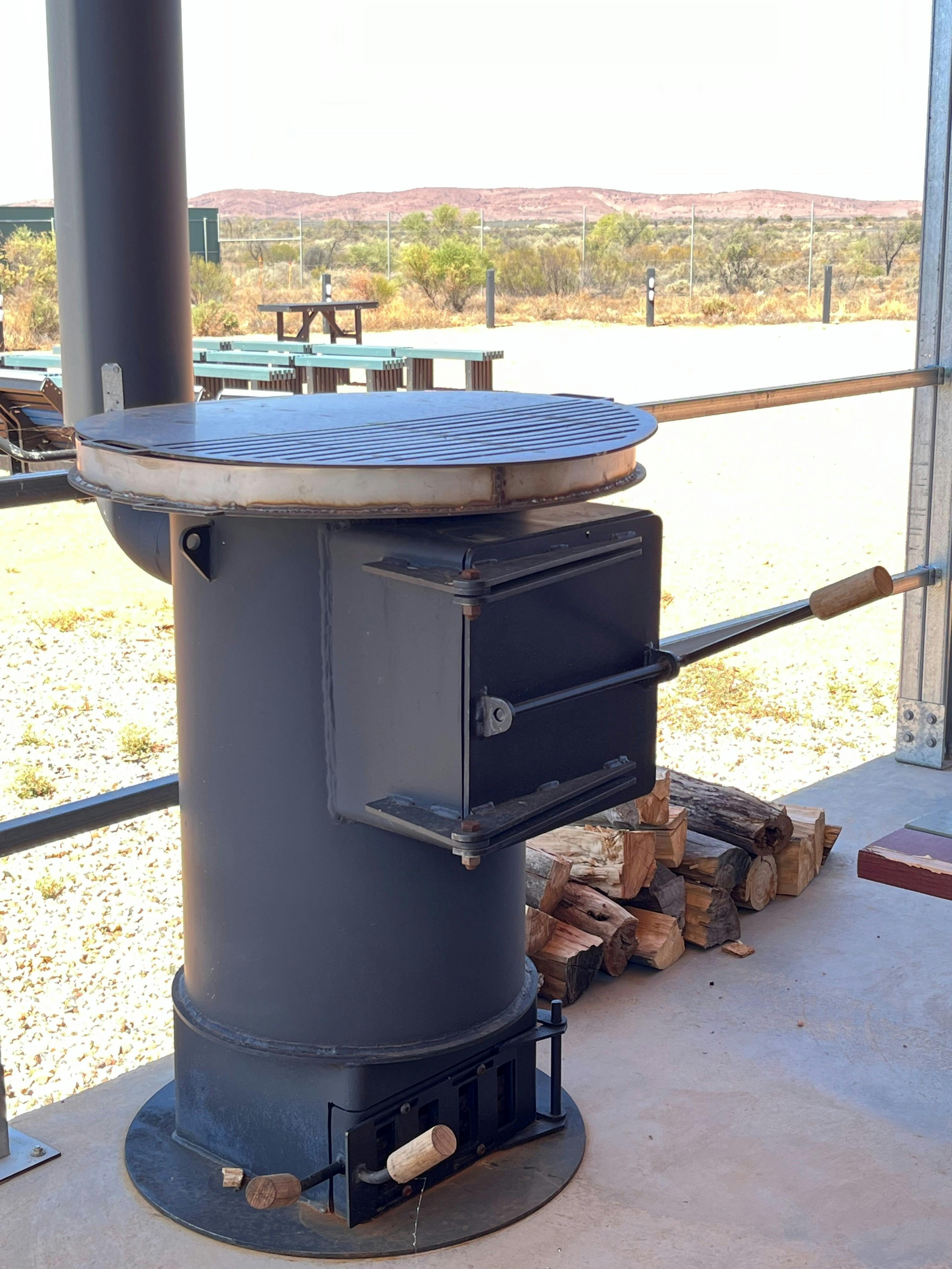 Potbelly heater with timber nearby and stargazing site in background.