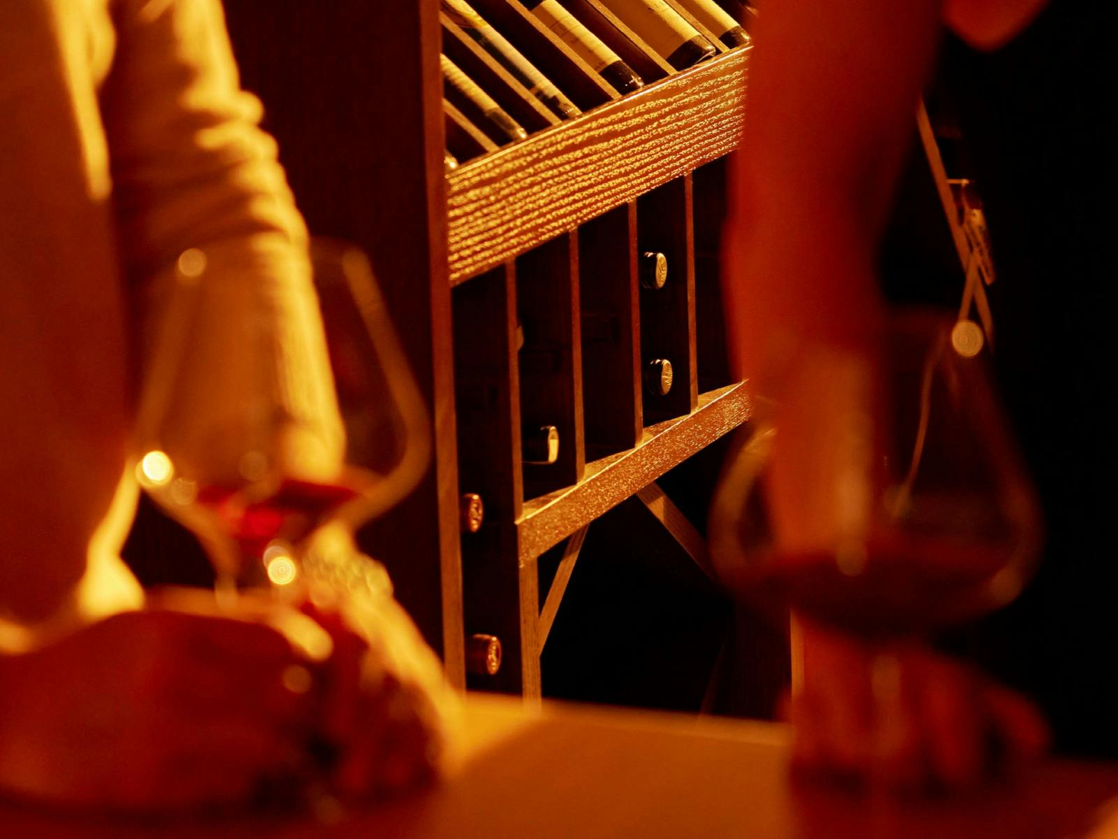 A wine tasting taking place with close crop of wine glasses in cellar