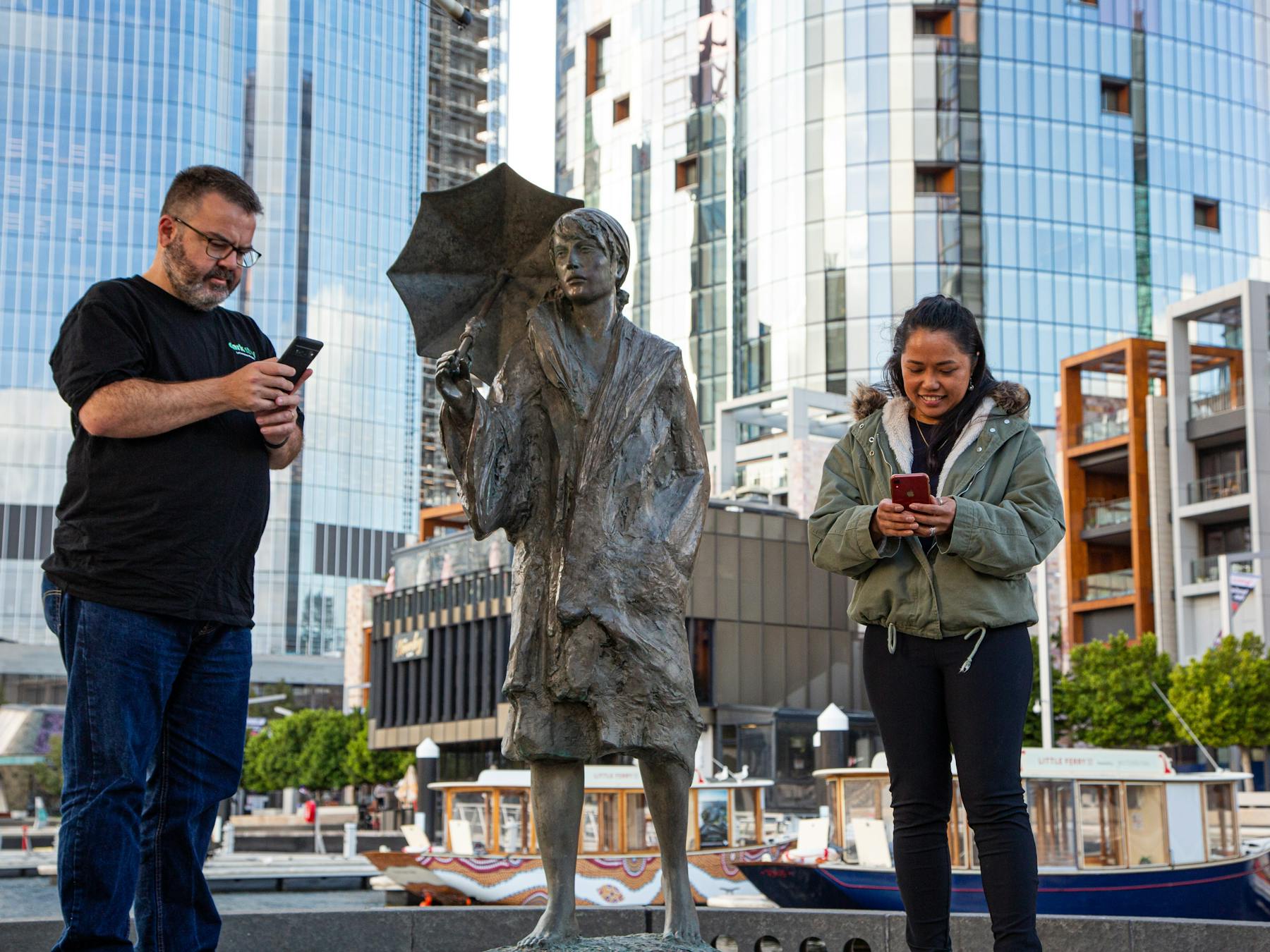 Two people looking at their phones next to a historical statue