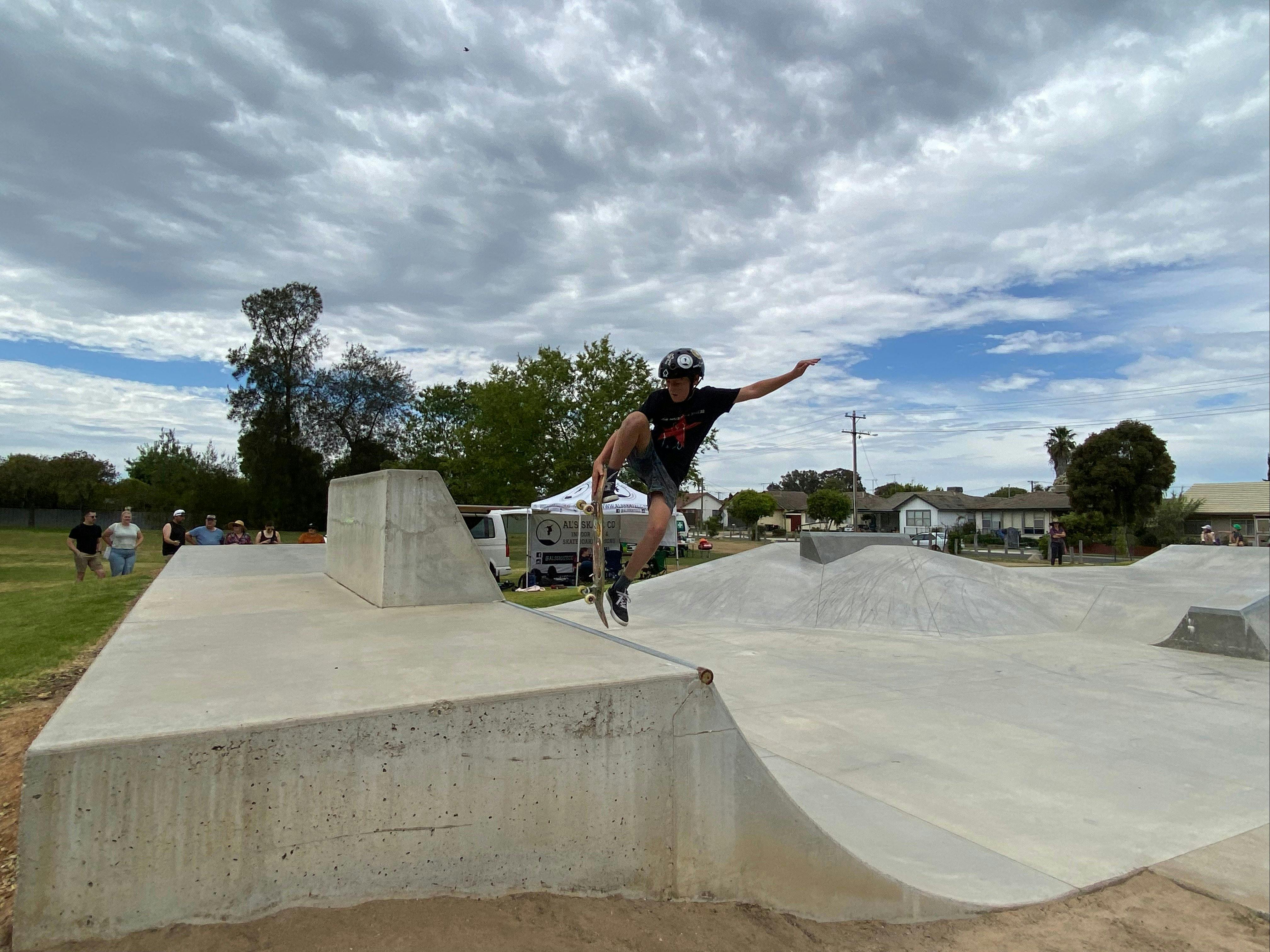 Skateboard rider coming off the cement bank in the air with other people watching