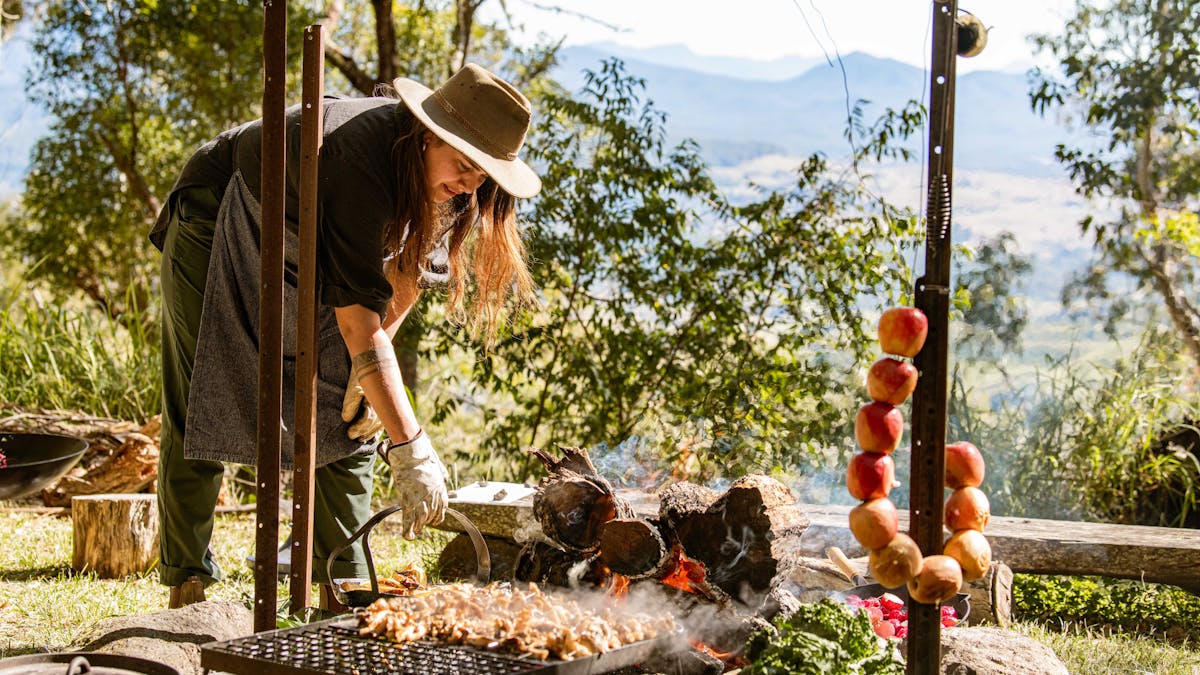 Lady cooking on campfire outdoors on top of mountain top in the Scenic Rim