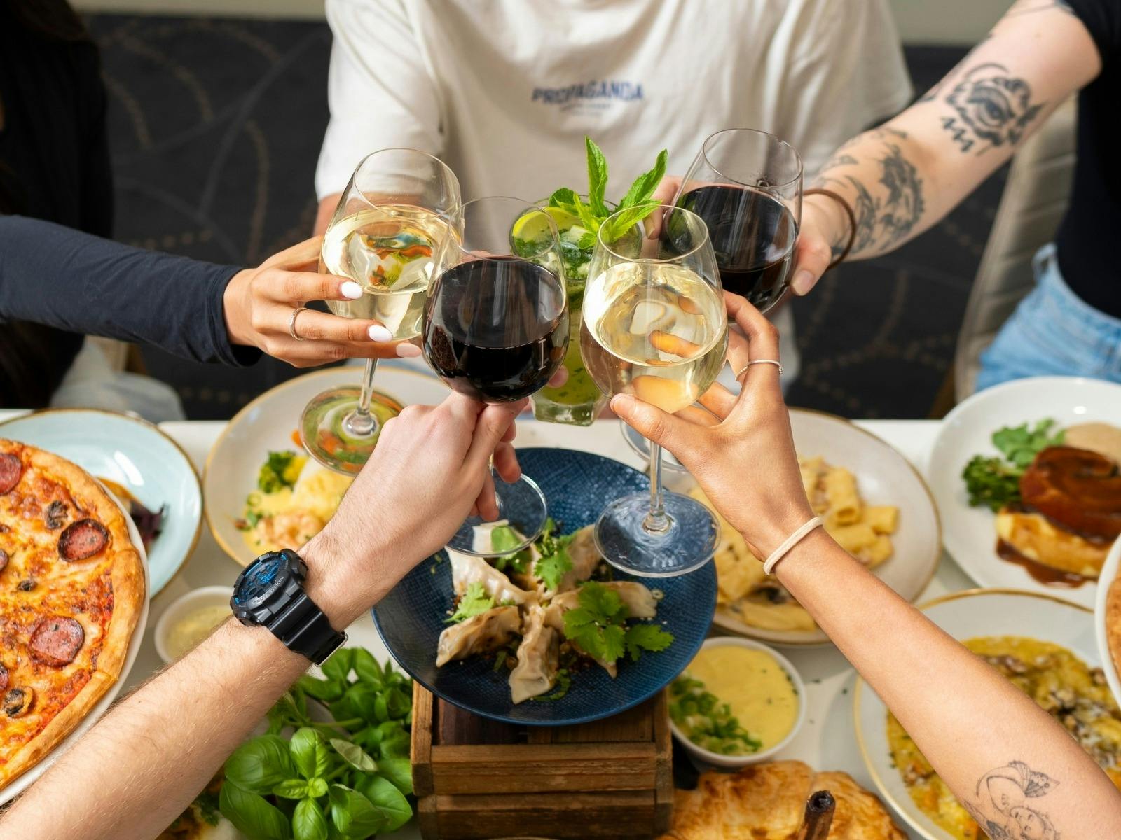 spread of food and people cheers drinks together at a function
