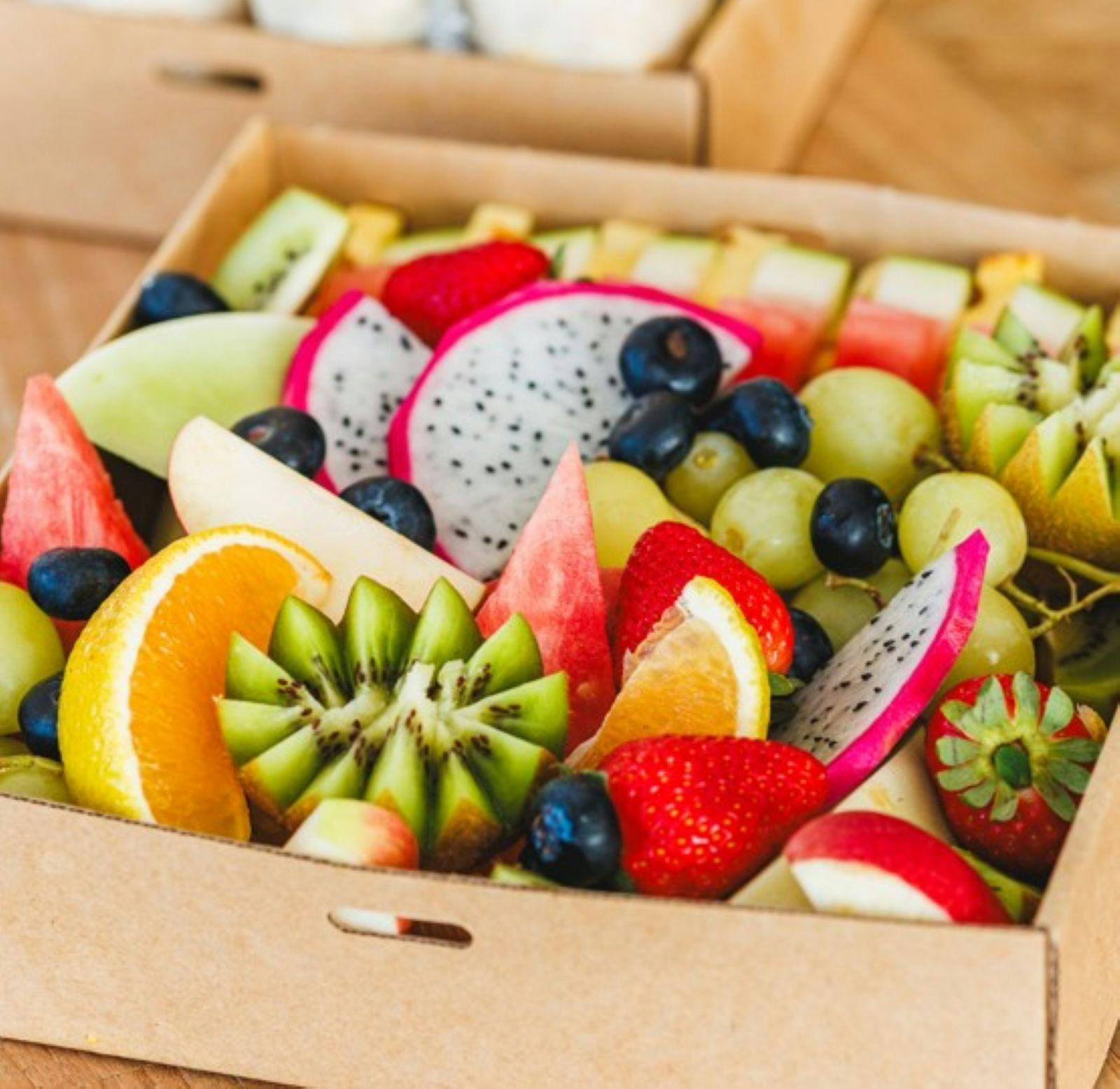 A serving box filled with a variety of cut  tropical fruits