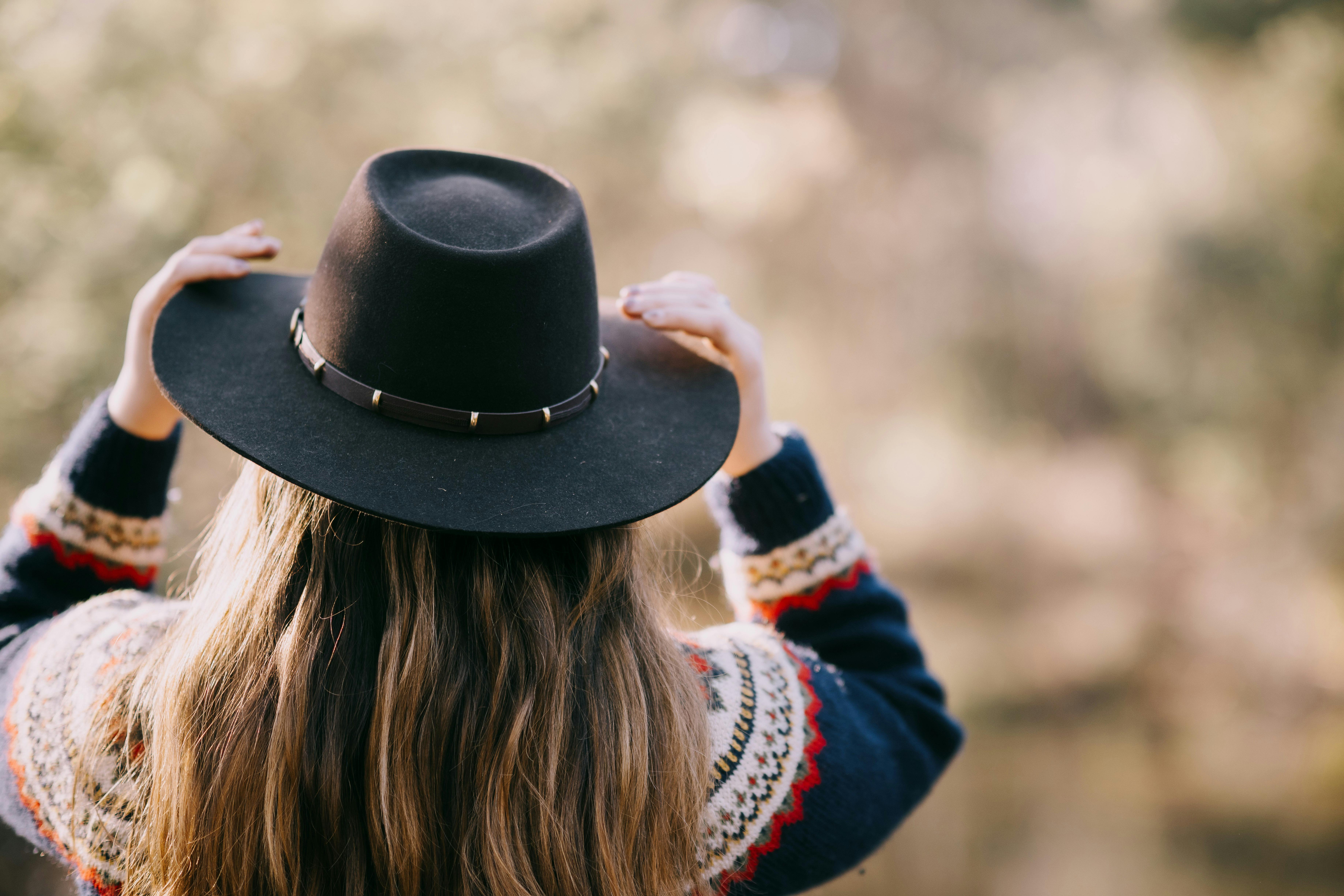 lady in the country wearing a cowboy hat, facing away from the camera