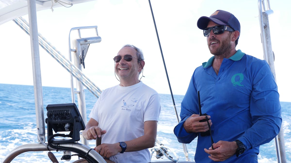 Guest taking the helm under watchful eye of the skipper Ocean Free sailing