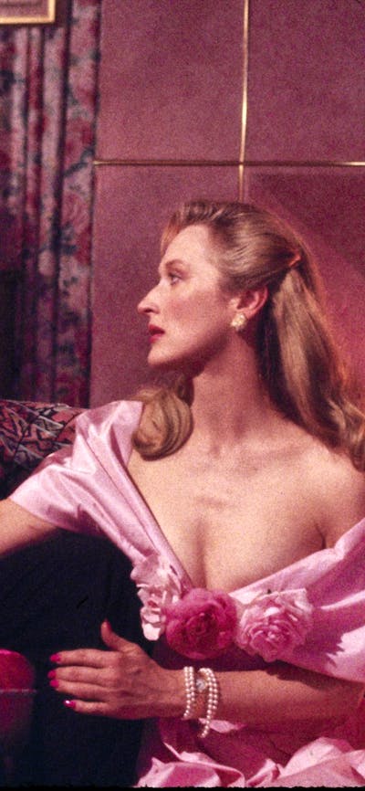 Woman wearing a pink gown with a wine glass clinking against another man's wine glass