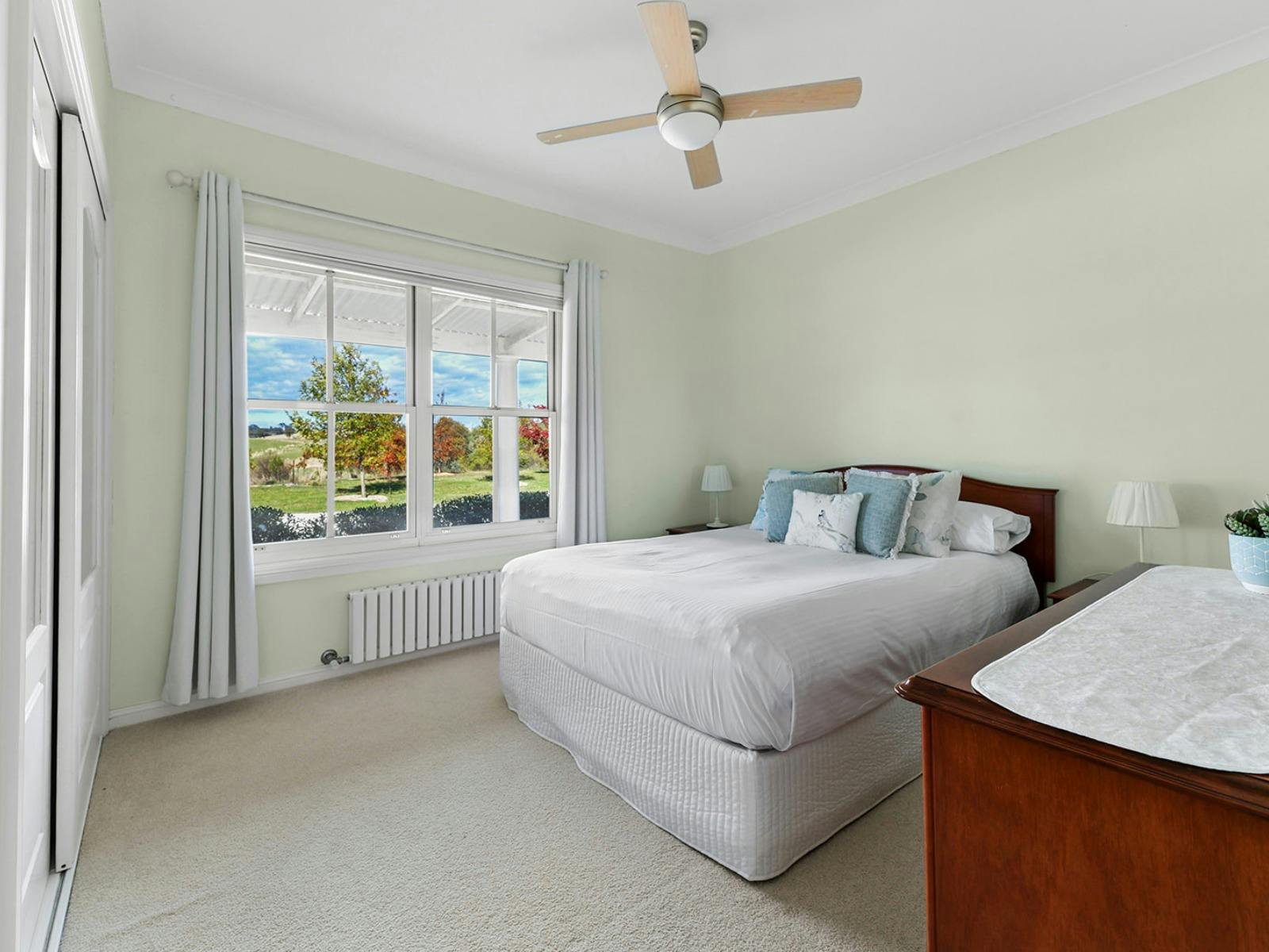 Bedroom with queen bed and dark wood furniture and a fan