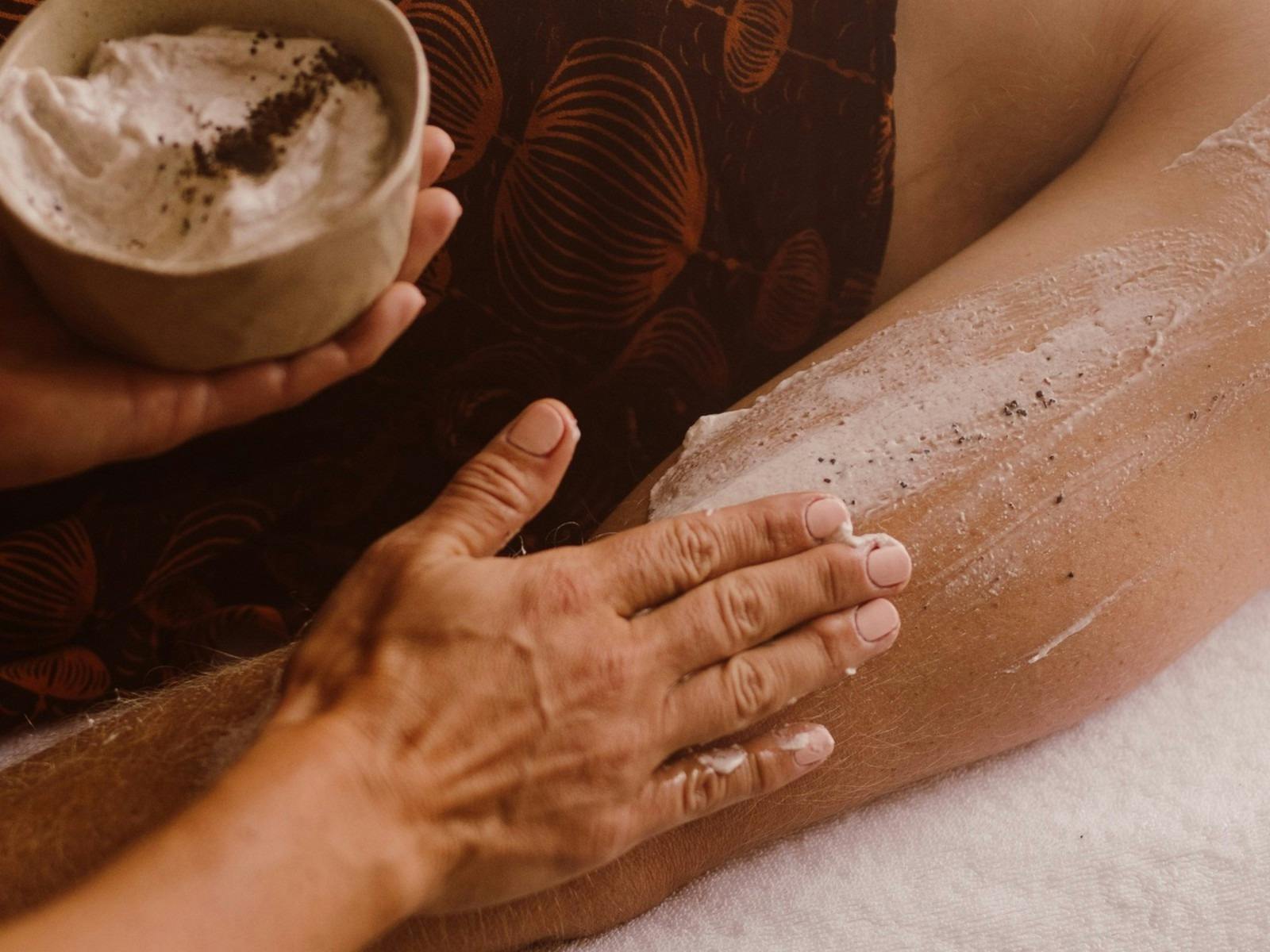 a woman's hand giving a woman's arm an exfoliation treatment