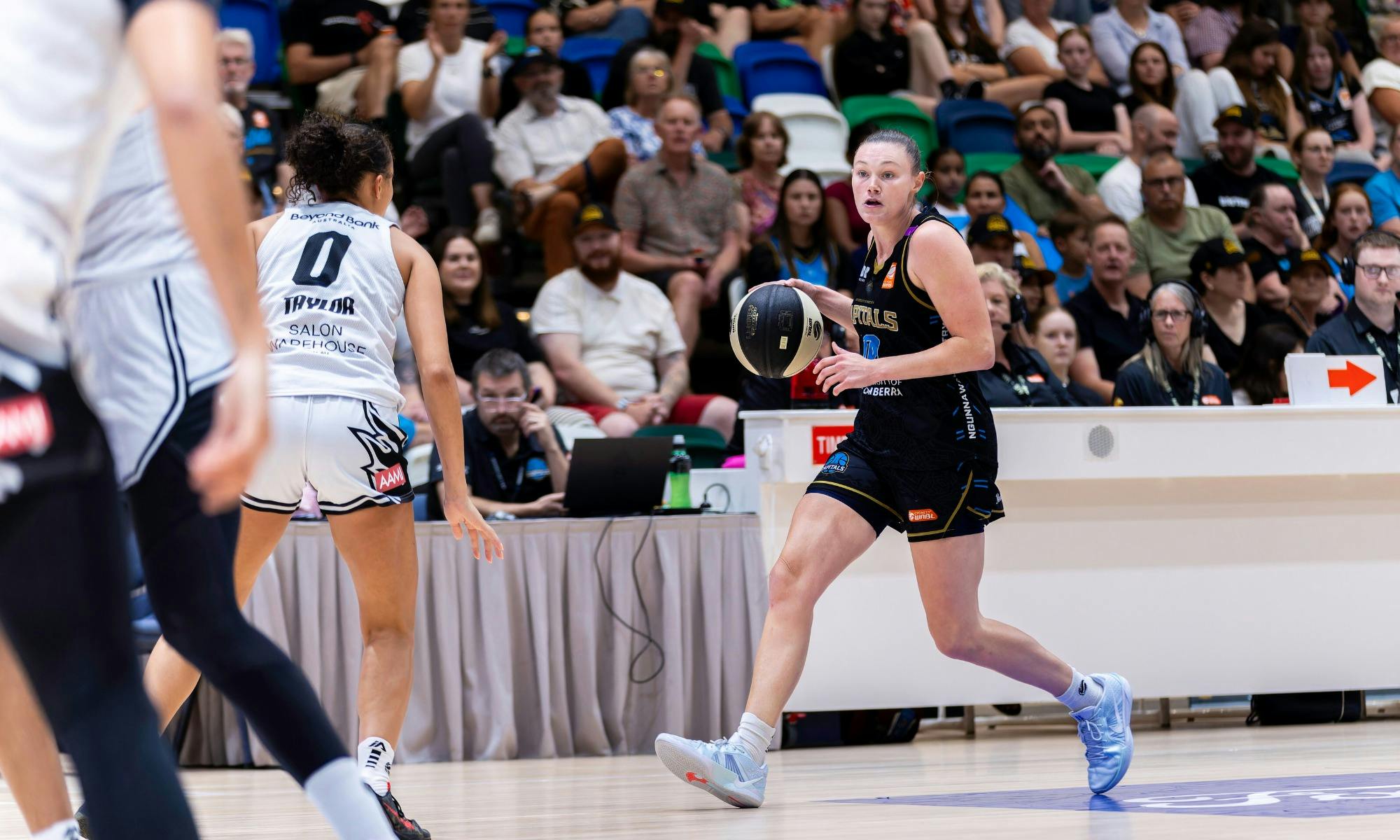 UC Capitals player dribbling a basketball while being defended.