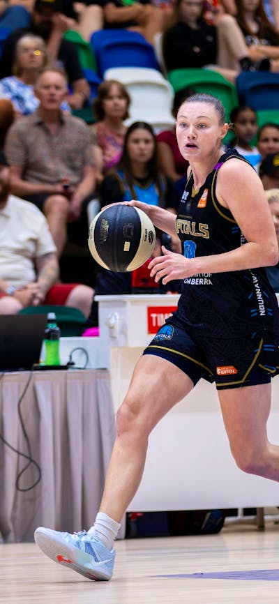UC Capitals player dribbling a basketball while being defended.