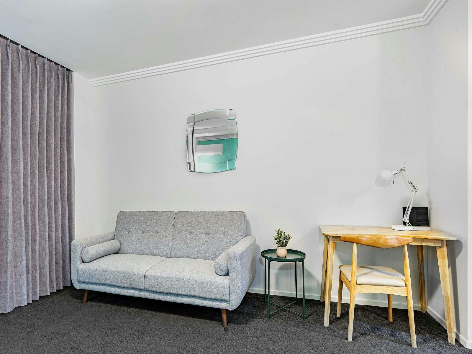 Additional angle of the sofa bed with small desk and wall décor.