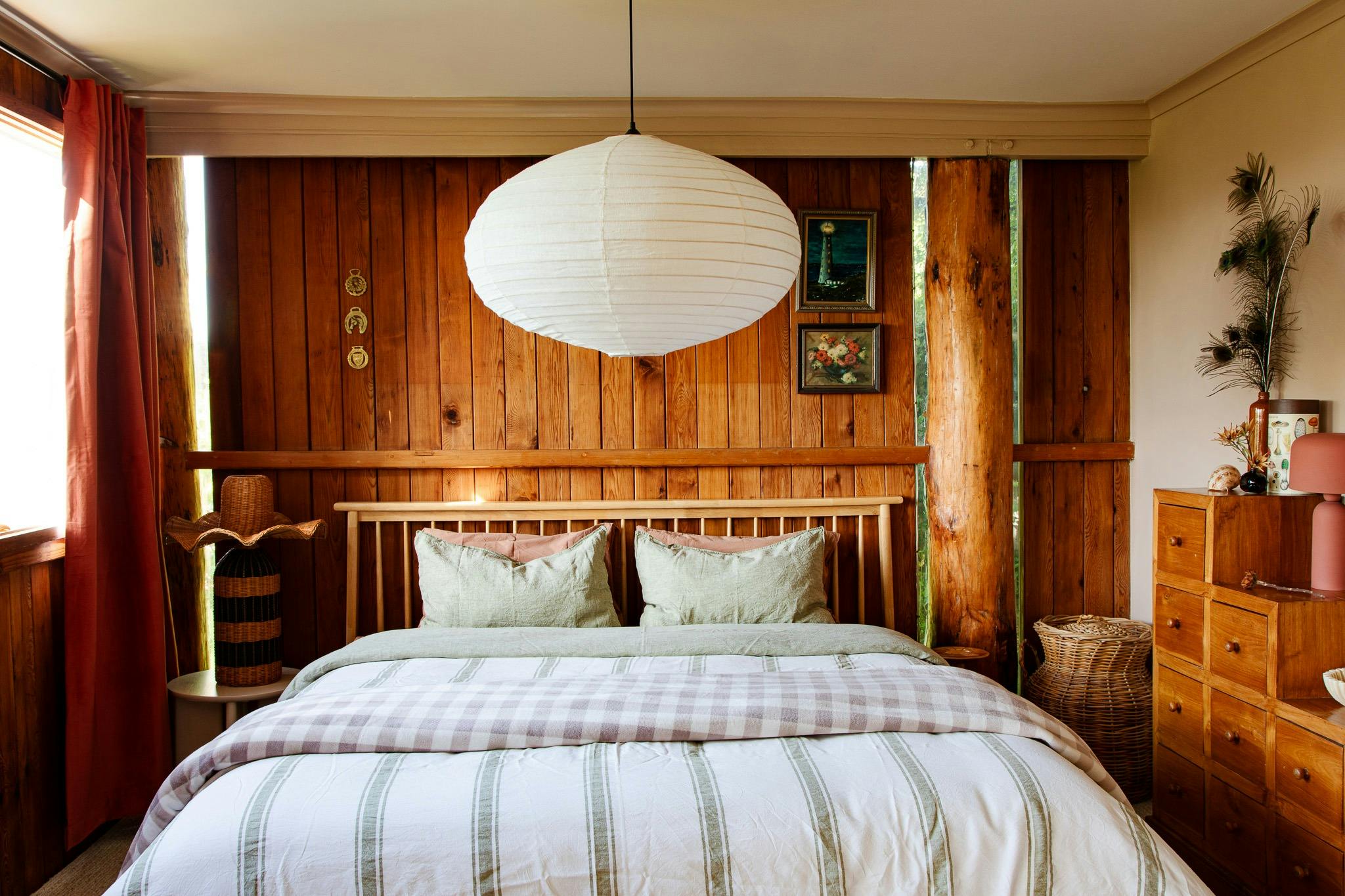 An image of an king bed draped in linen and a hanging pendant lantern.