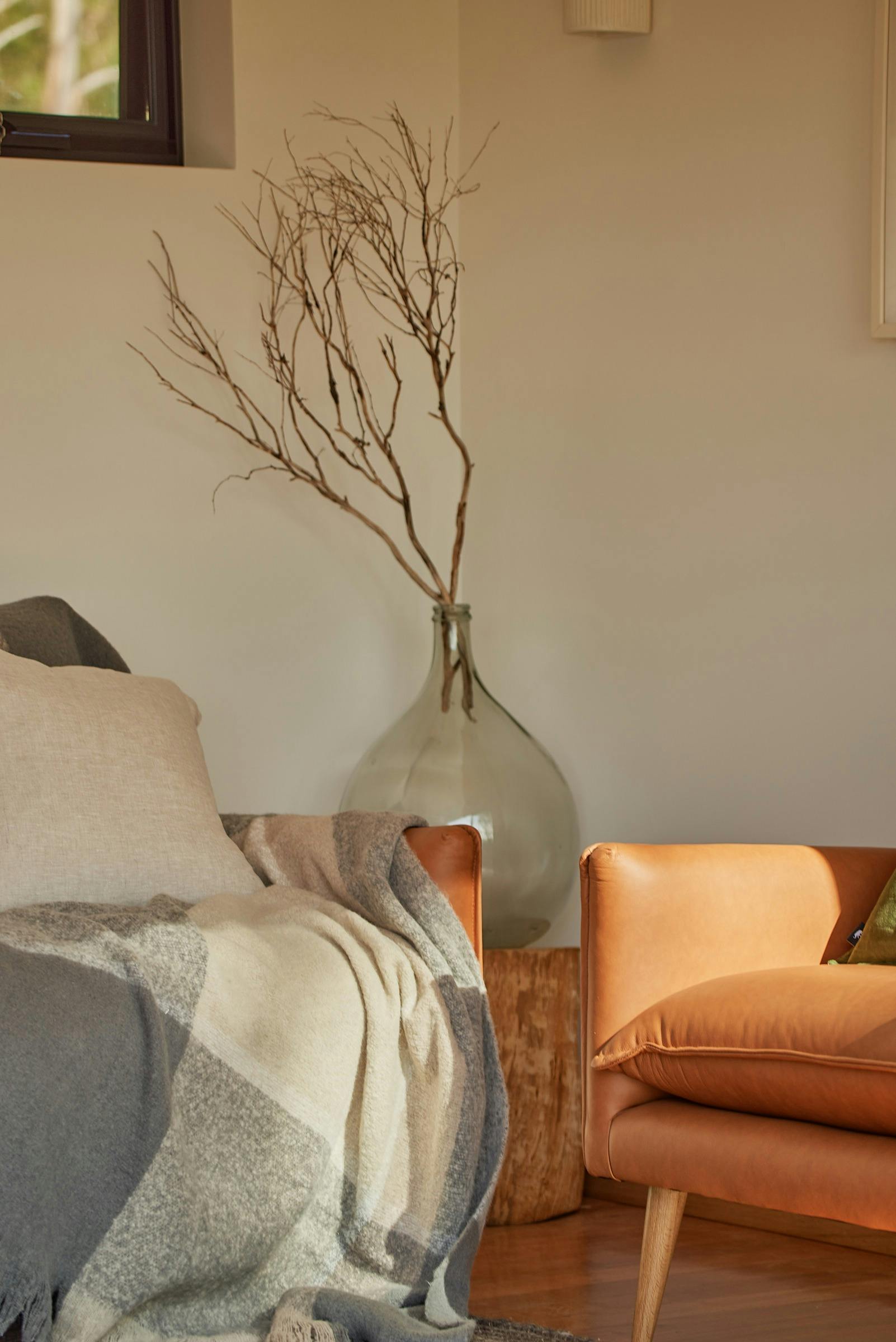 Image of tan couch with throw rug and cushion and large vase