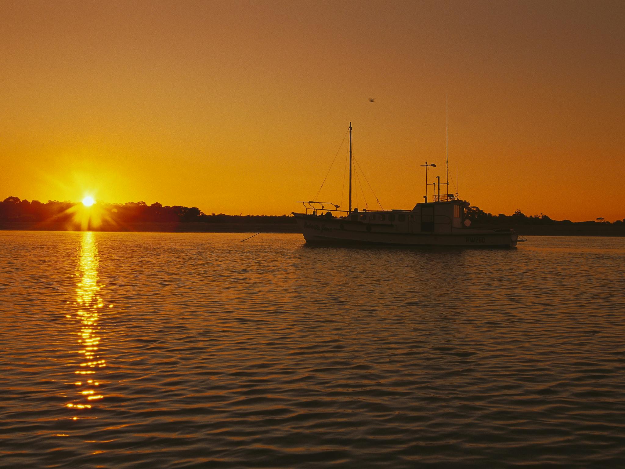 photo of sailing boat in a setting sun on the Great Sandy Strait photo of sailing boat in a setting sun on the Great Sandy Strait