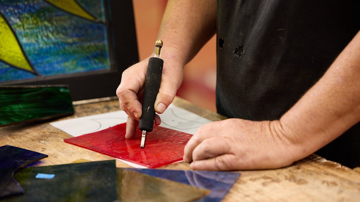 Person working on stained glass with tool.