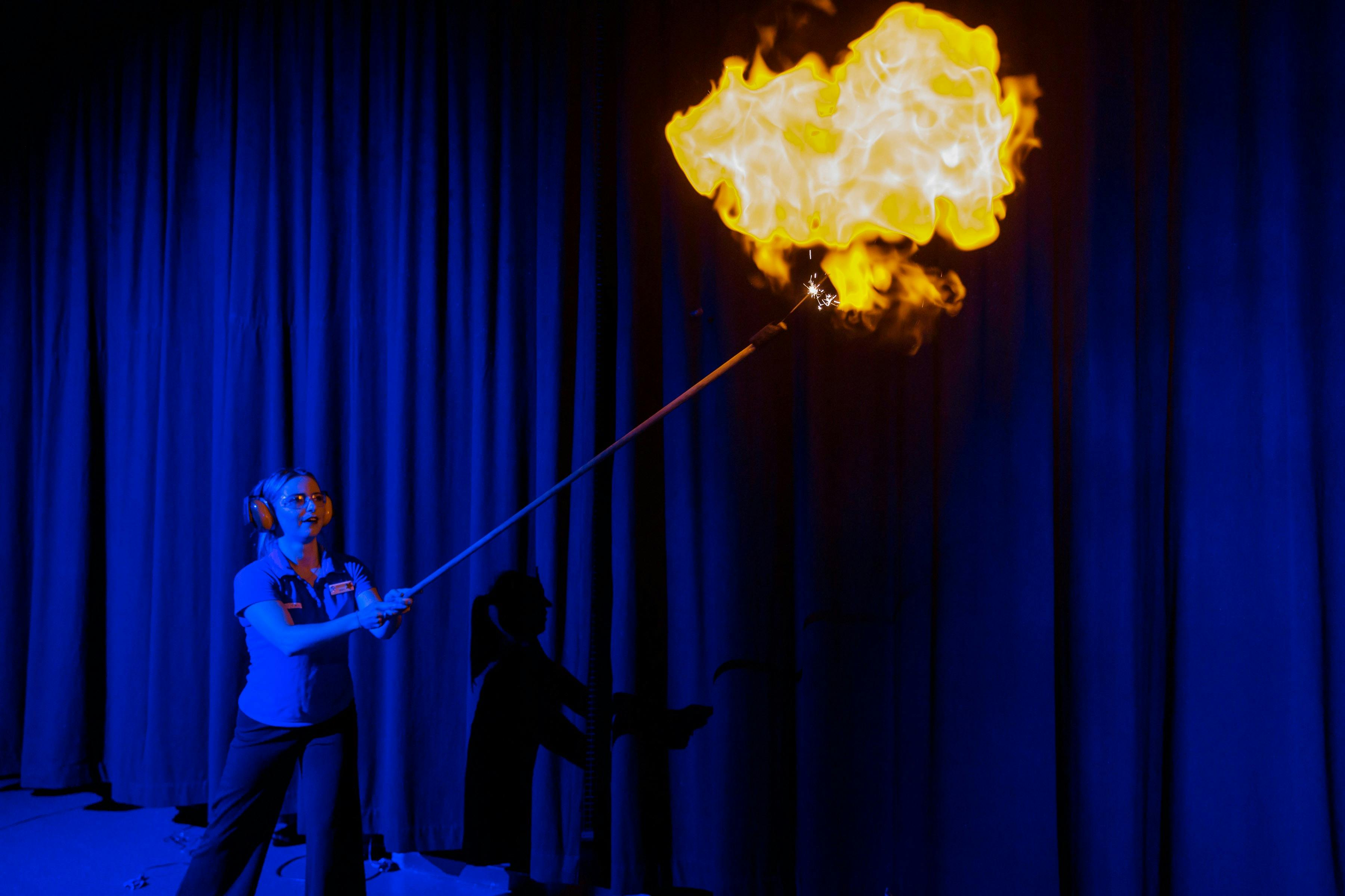Person wearing earmuffs and lighting a hydrogen balloon on fire